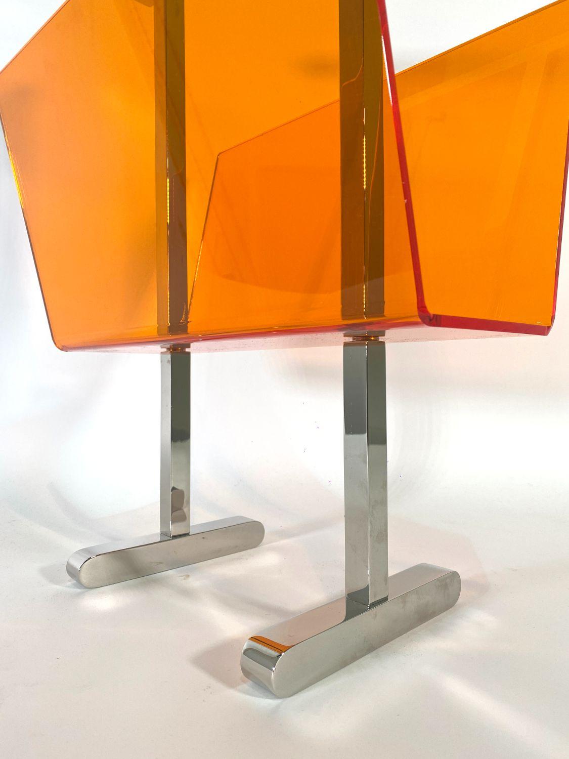 The polished nickel stand with orange lucite magazine holder- these pieces are part of Charles Hollis Jones new line of colored lucite pieces- we are proud to exclusively represent this line- production will be limited to 12 pieces only- 11 for sale