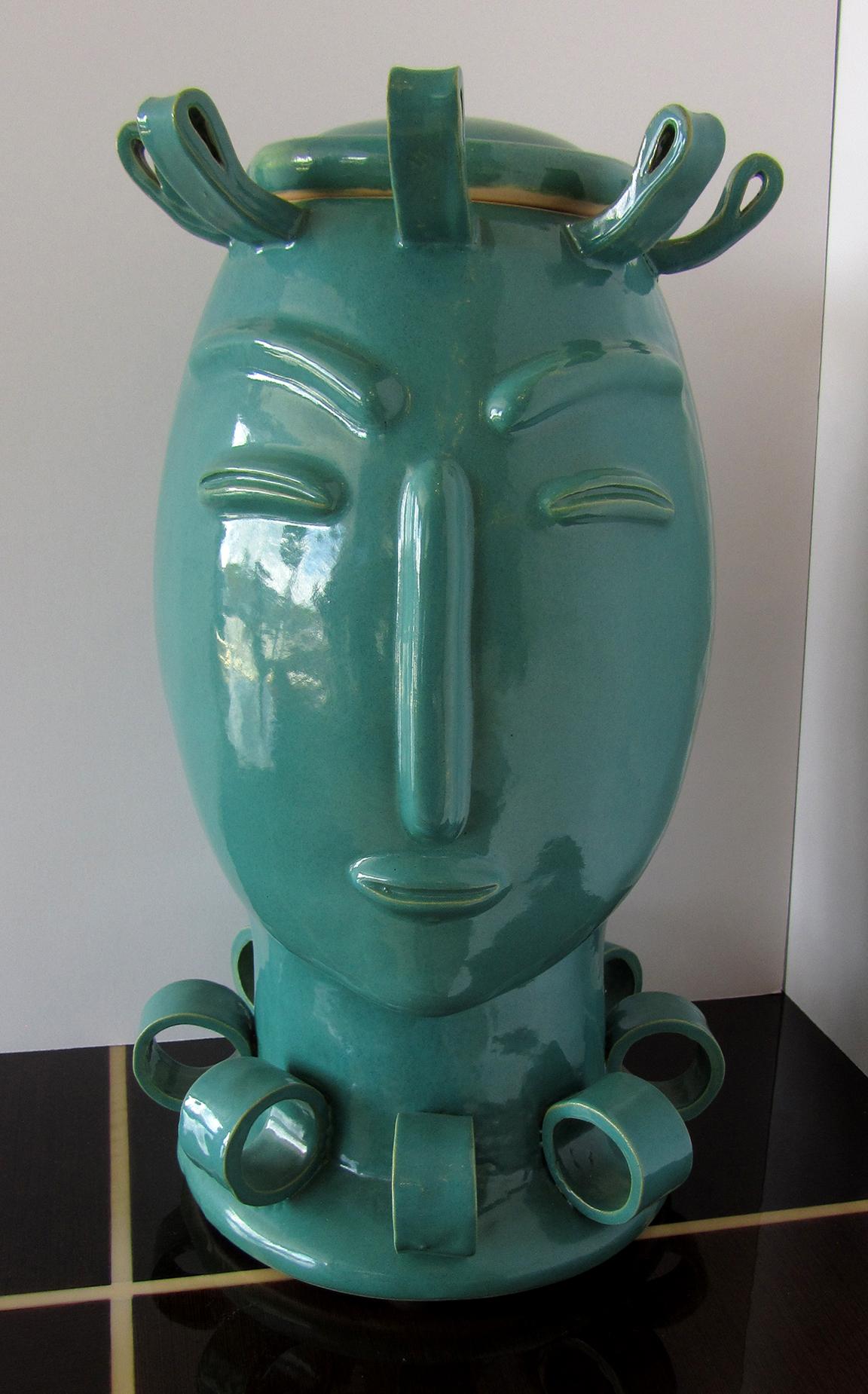 A beautiful deco revival style, covered jar of a head of a woman. The aqua-green glaze will make this decorative piece a focal point of any area. The woman's face has stylized features.