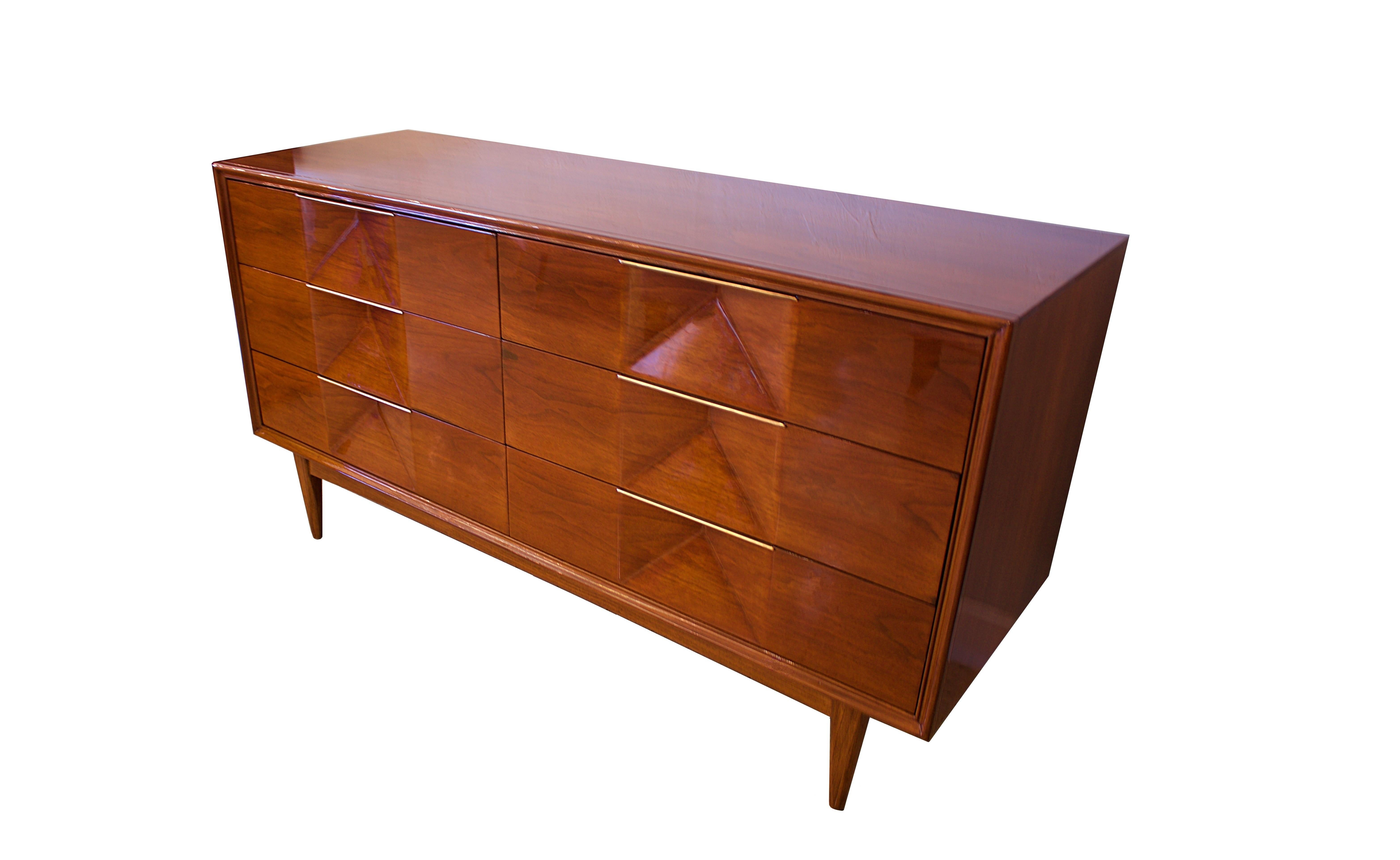 The rectangular top above 6 drawers with geometric motif and brass details, on round tapering legs.
 