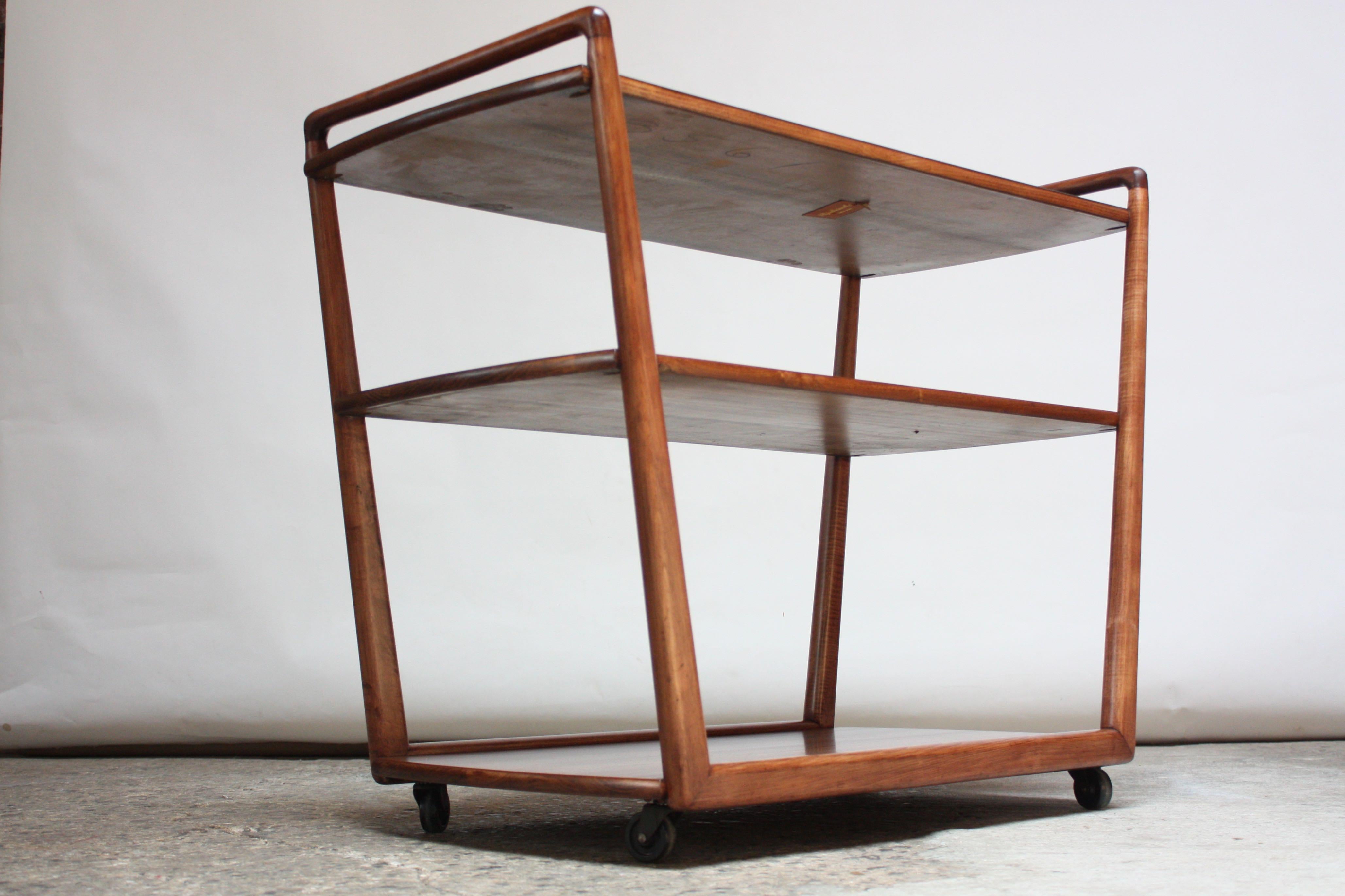 1950s three-tier sculpted walnut bar cart / serving trolley on caster wheels with a black laminated top shelf manufactured by the J. B. Van Sciver Co. of Camden, New Jersey (1881-1984). Nice, refinished condition with some light scratches to the