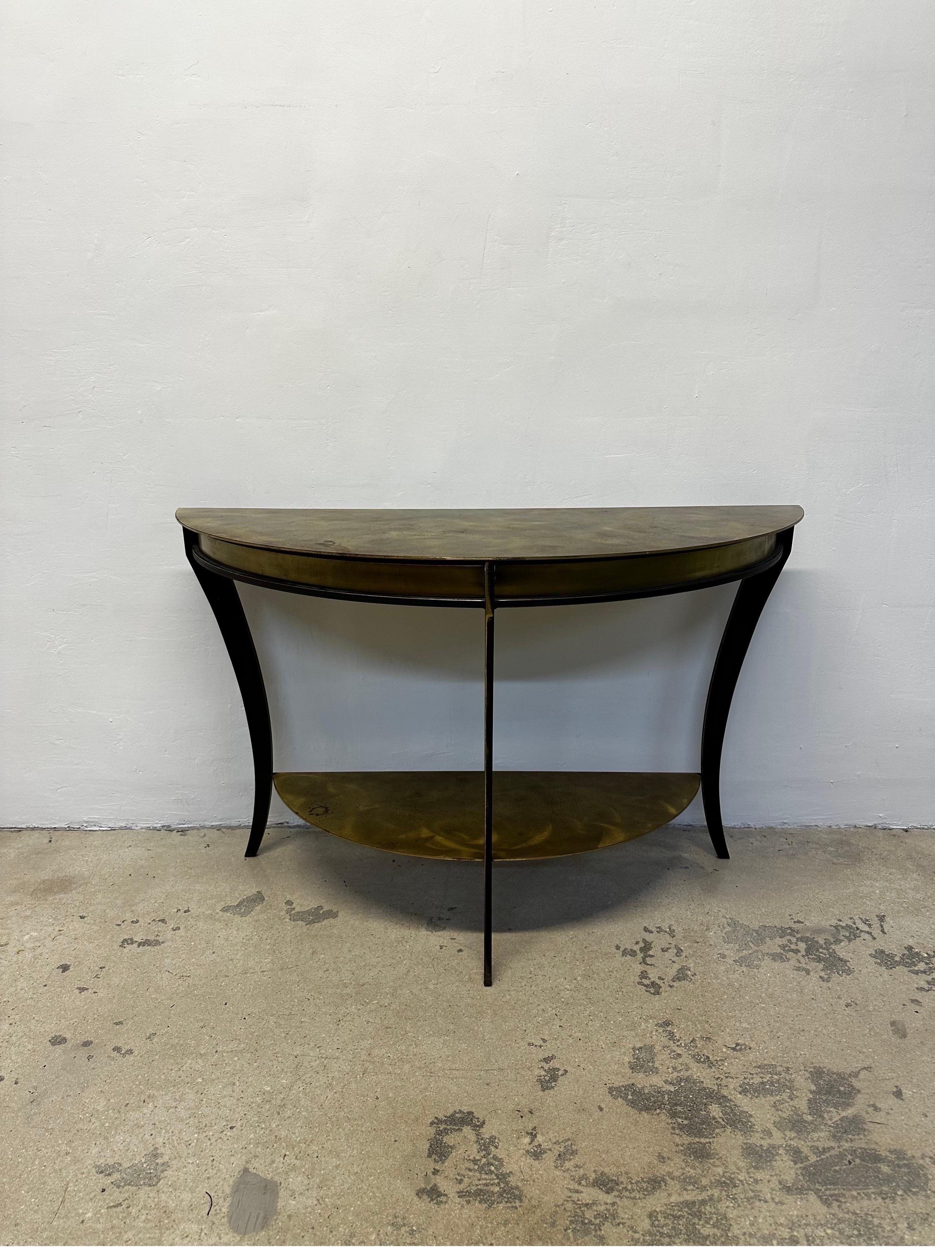 American Mid-Century Modern welded steel demilune console table with brass surfaces. The brass has a swirl effect and is patinated with age and use.