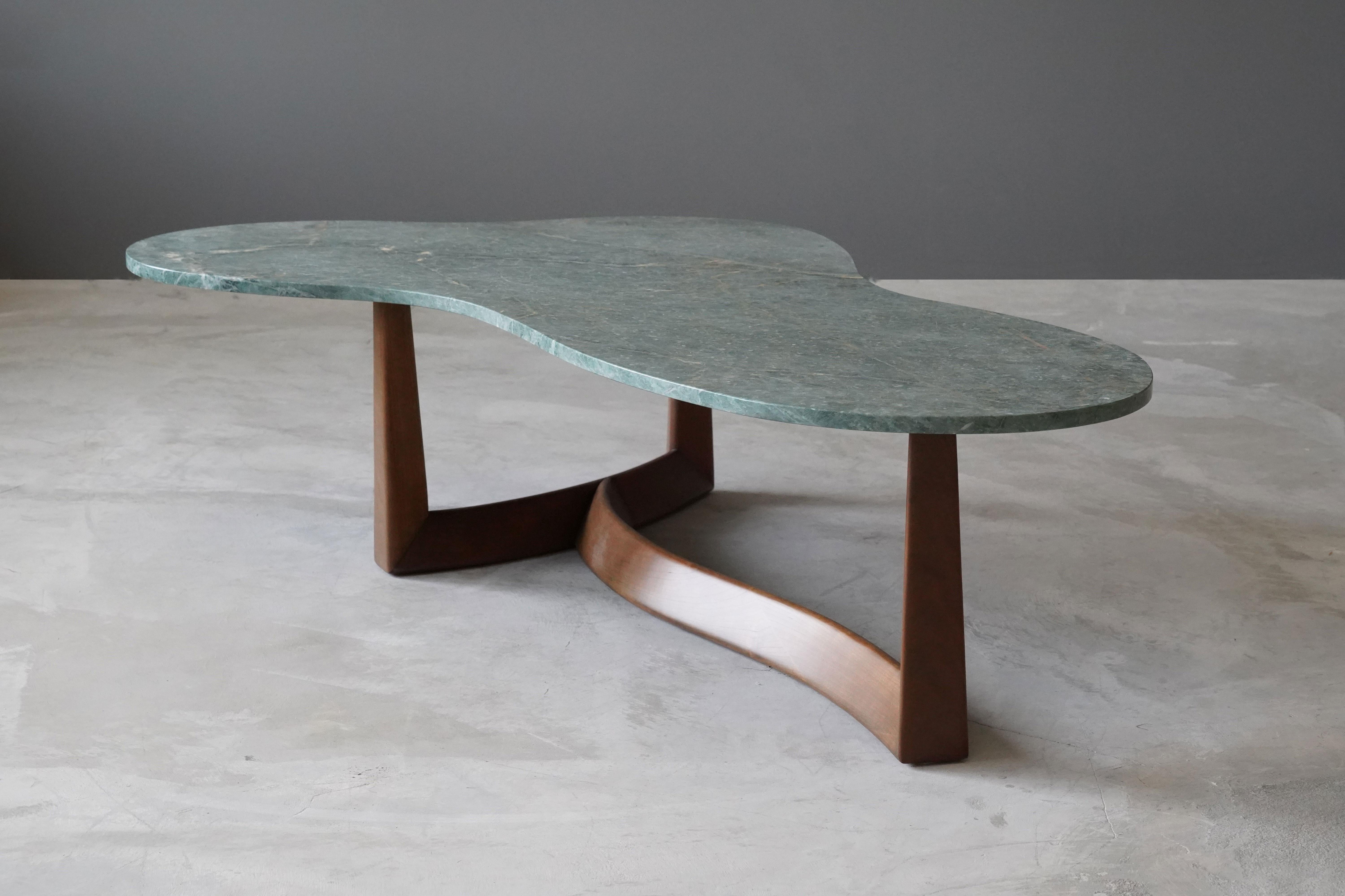 A rare and organic coffee / cocktail table. Produced in America, 1950s. The marble top rests on a finely sculpted walnut base. Possibly designed by T.H. Robsjohn-Gibbings. 

