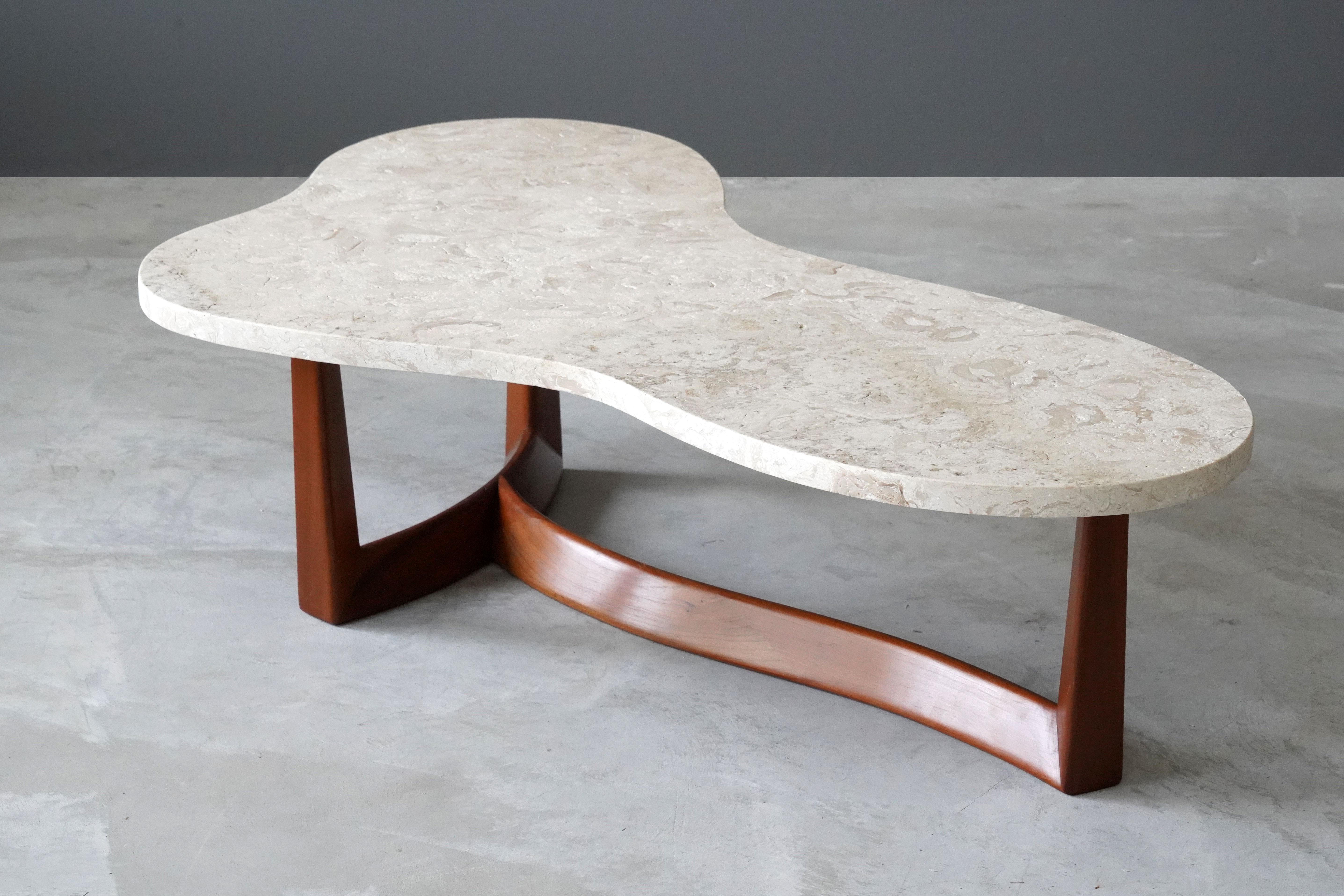 A rare and organic coffee or cocktail table. Produced in America, 1950s. The marble top rests on a finely sculpted walnut base. Possibly designed by T.H. Robsjohn-Gibbings. 

Other designers of the period include Paul Frankl, Tommi Parzinger, and