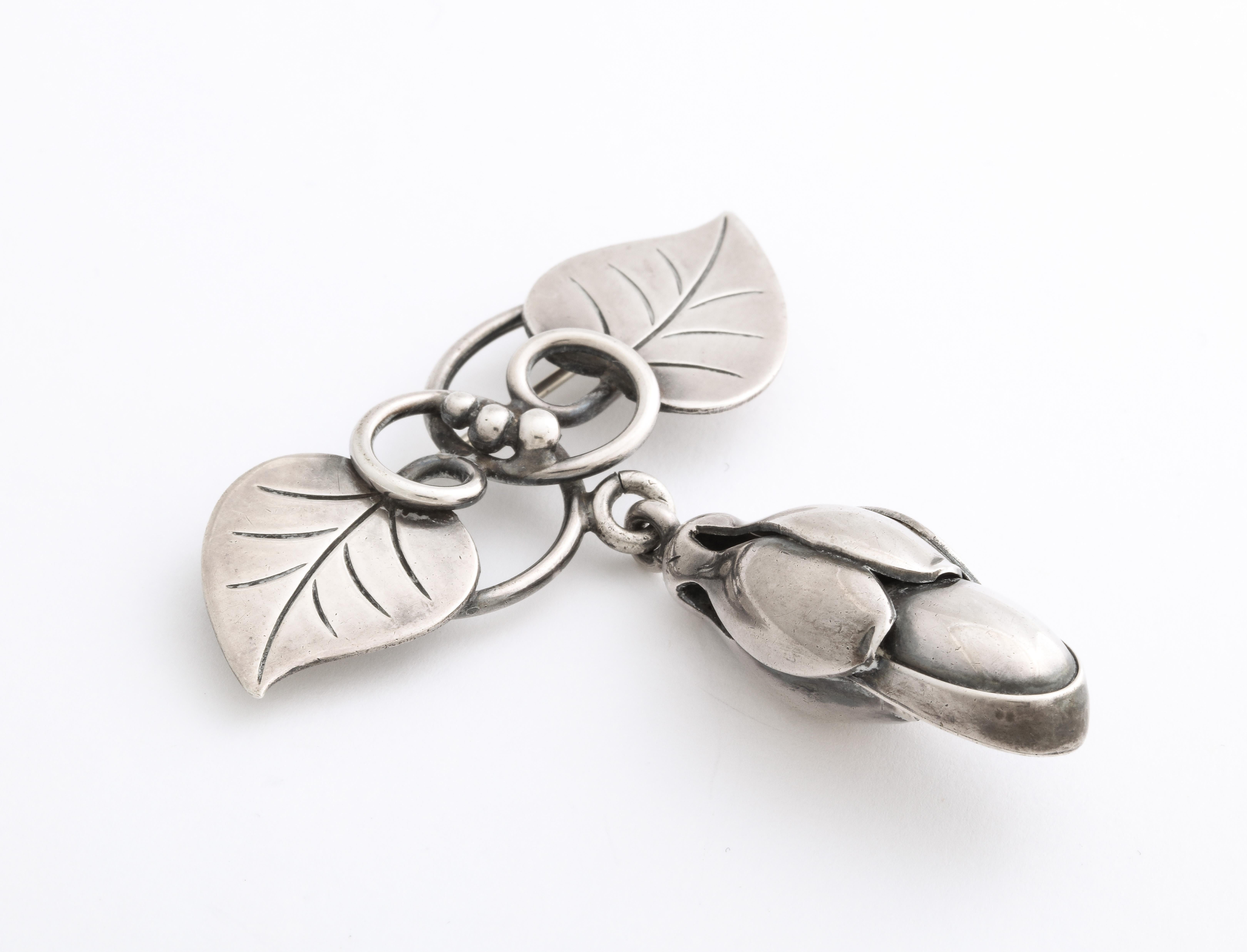 A realistic La Paglia silver floral bud suspends from a vine and two leaves. We love the movable nature of this brooch, the swirls and silver beading. The brooch is refined and elegant and appears to be Danish but is American Modernist in style made