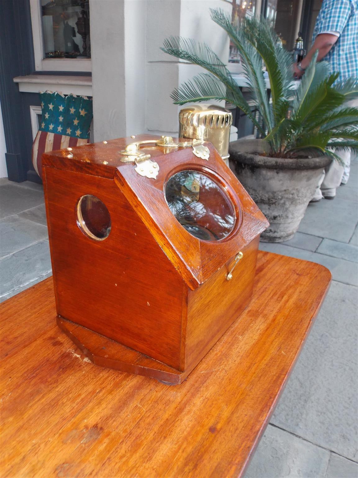 American nautical mahogany yacht binnacle with a hinged locking oval glass viewing port, original removable brass side light burner with font, brass carrying handle, and fitted with an interior compass by D. Baker- Melrose, Massachusetts, Late 19th