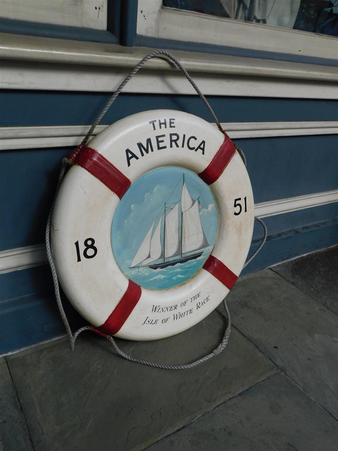 American nautical painted life ring with two masted sailing vessel, us flag, and decorative outer roping, isle of white race. Mid 19th century.