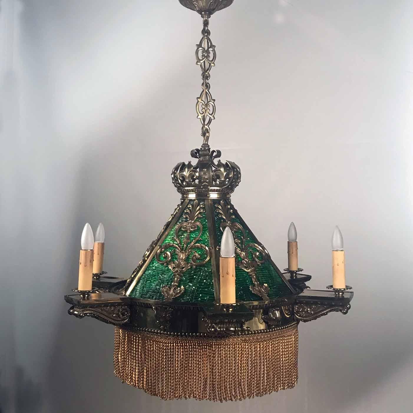 This late 19th century American chandelier equally lights a room and the table below. The cased green glass panels are set in a gilt bronze hexagonal frame, surmounted by a crown-shaped cap with original pierced suspension chain and canopy. The base