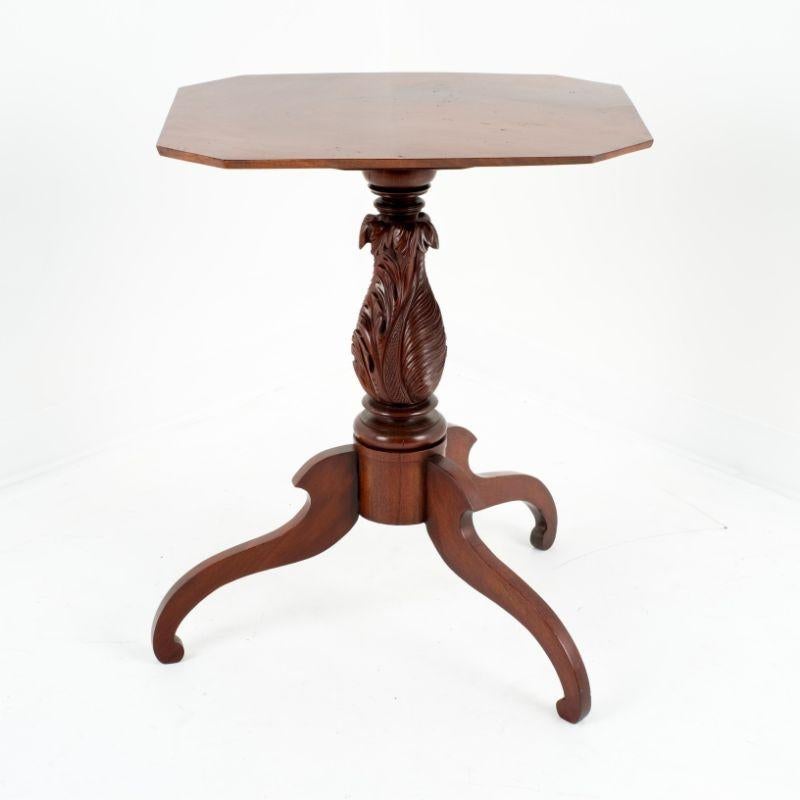 American neoclassical rectangular single board tilt top tea table of dramatically figured mahogany with clipped corners. The top is supported by a turned and superbly feather carved mahogany pedestal shaft on tripod spider leg base.
American, New
