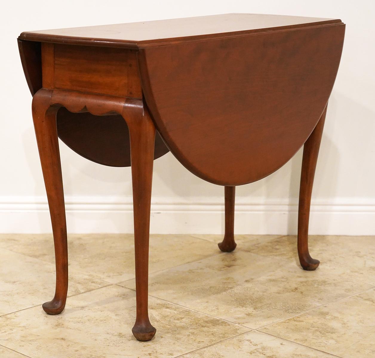 This fine New England Queen Anne Style drop-leaf table is made of high quality cherrywood of great color with one plank top and leaves. Two legs swing out to support the leaves when open. The skirts at both ends are beautifully carved and shaped.