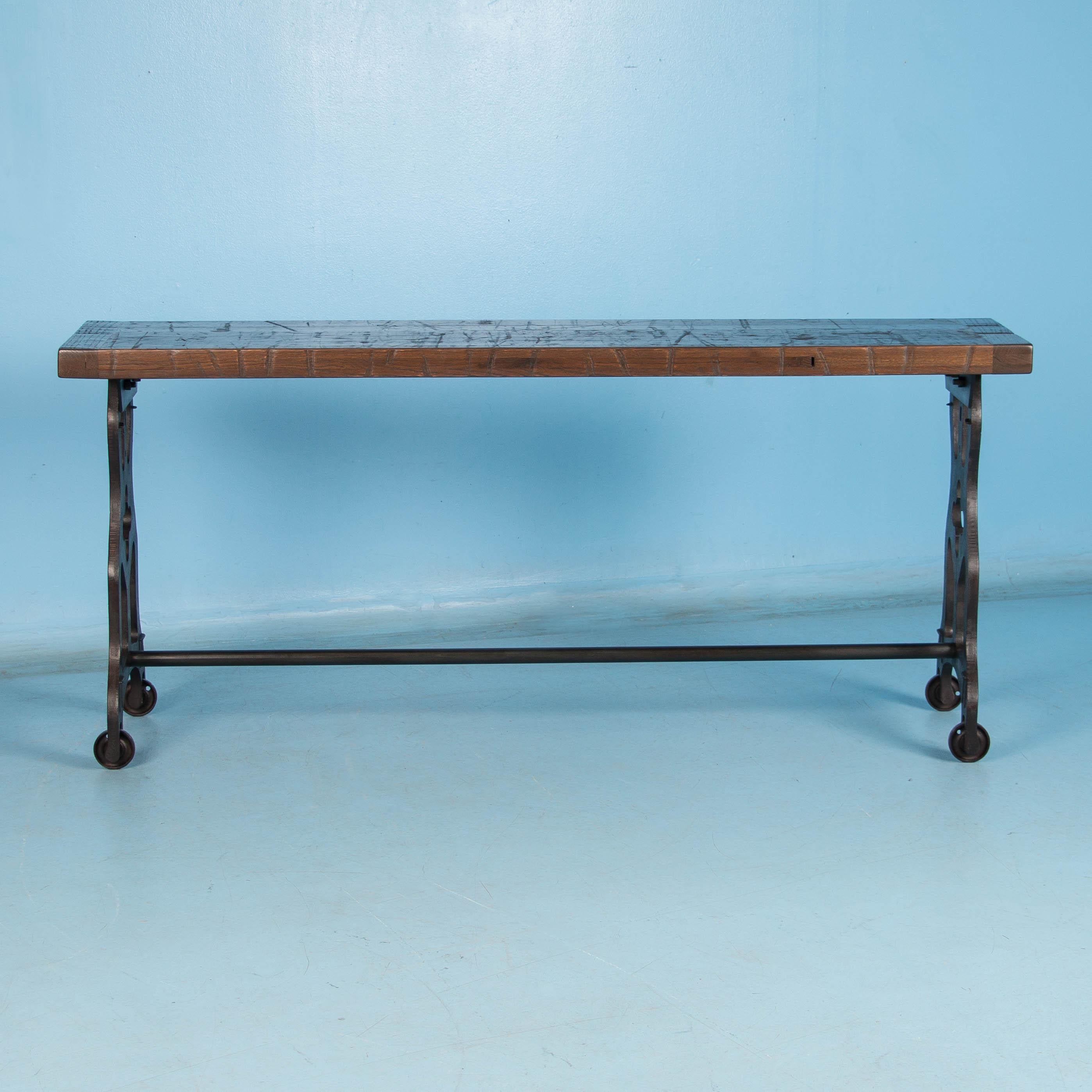 Made in the USA from reclaimed railroad box car flooring, the top is solid vintage oak. This long console table features antique cast iron legs that come from Danish industrial machinery. The rustic top has a durable finish and the iron stretcher