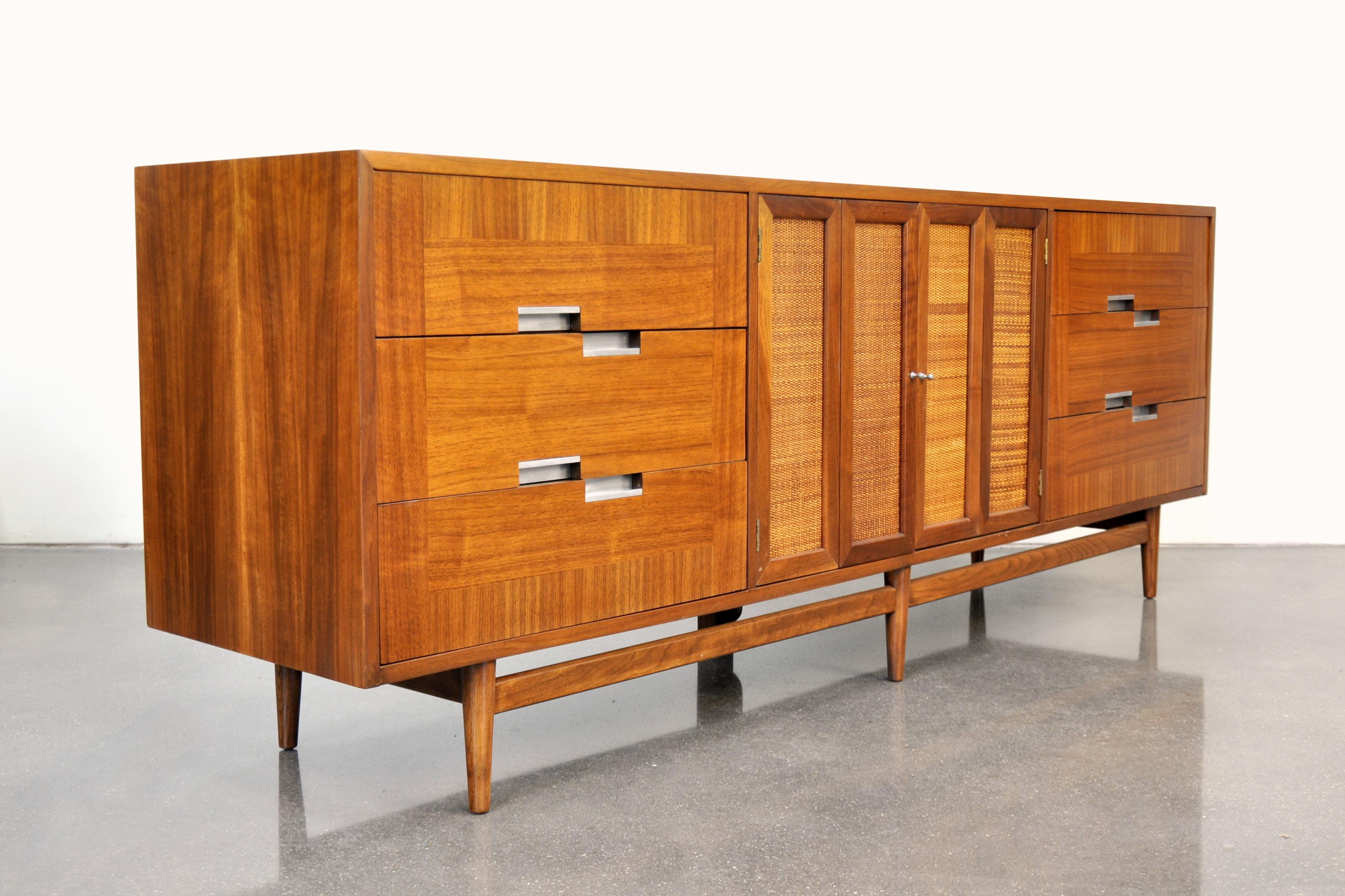 A gorgeous 7 foot long Mid-Century Modern walnut credenza from the desirable Accord line manufactured by American of Martinsville in the 1960s. The dresser features three drawers with aluminum pulls on the left and right sides centering a pair of