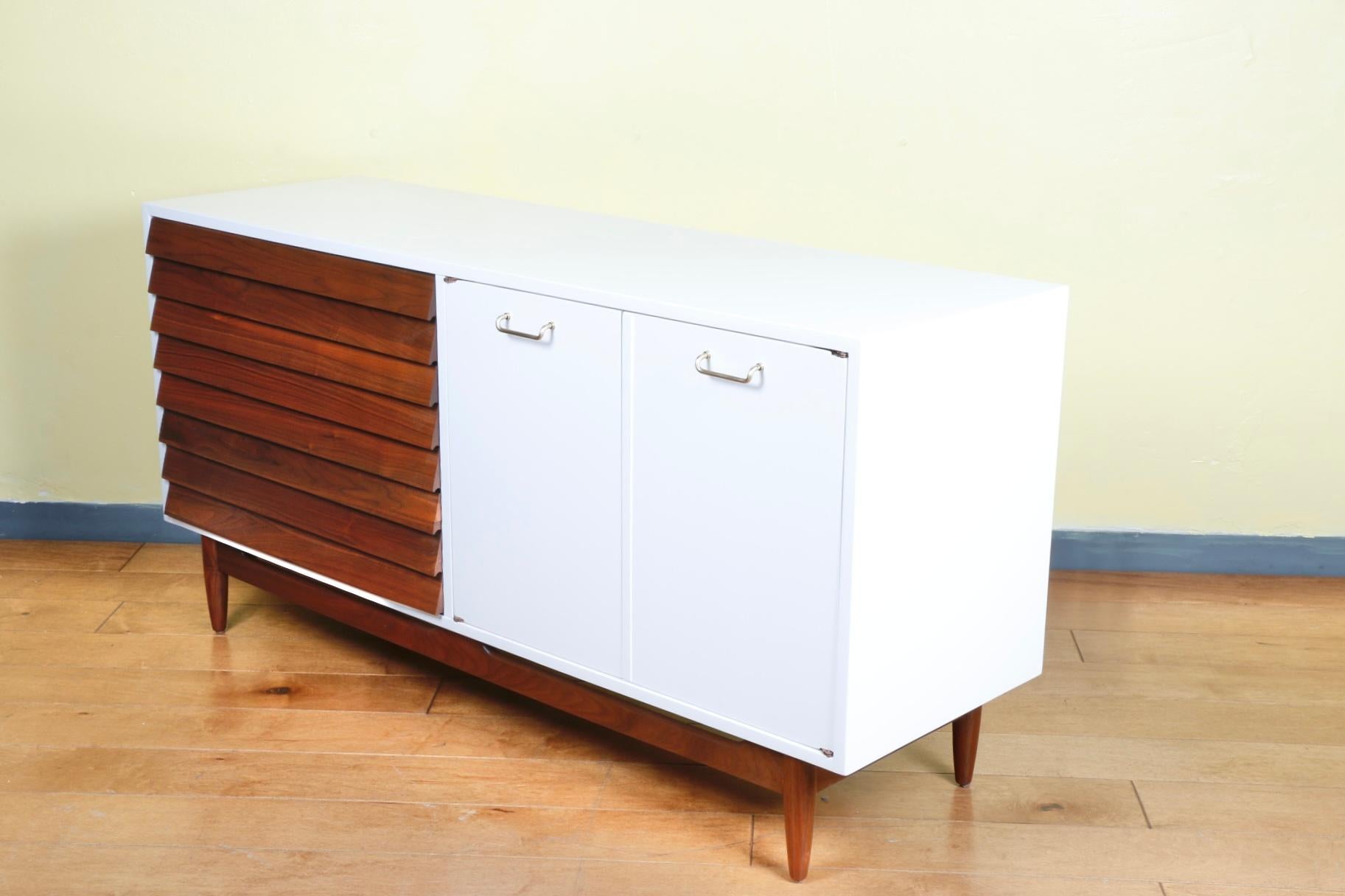 Gorgeous refinished walnut credenza painted white with walnut accent wood left side drawers. Great design and style with brass handles. Are drawers and doors work well. Base is sturdy and strong.