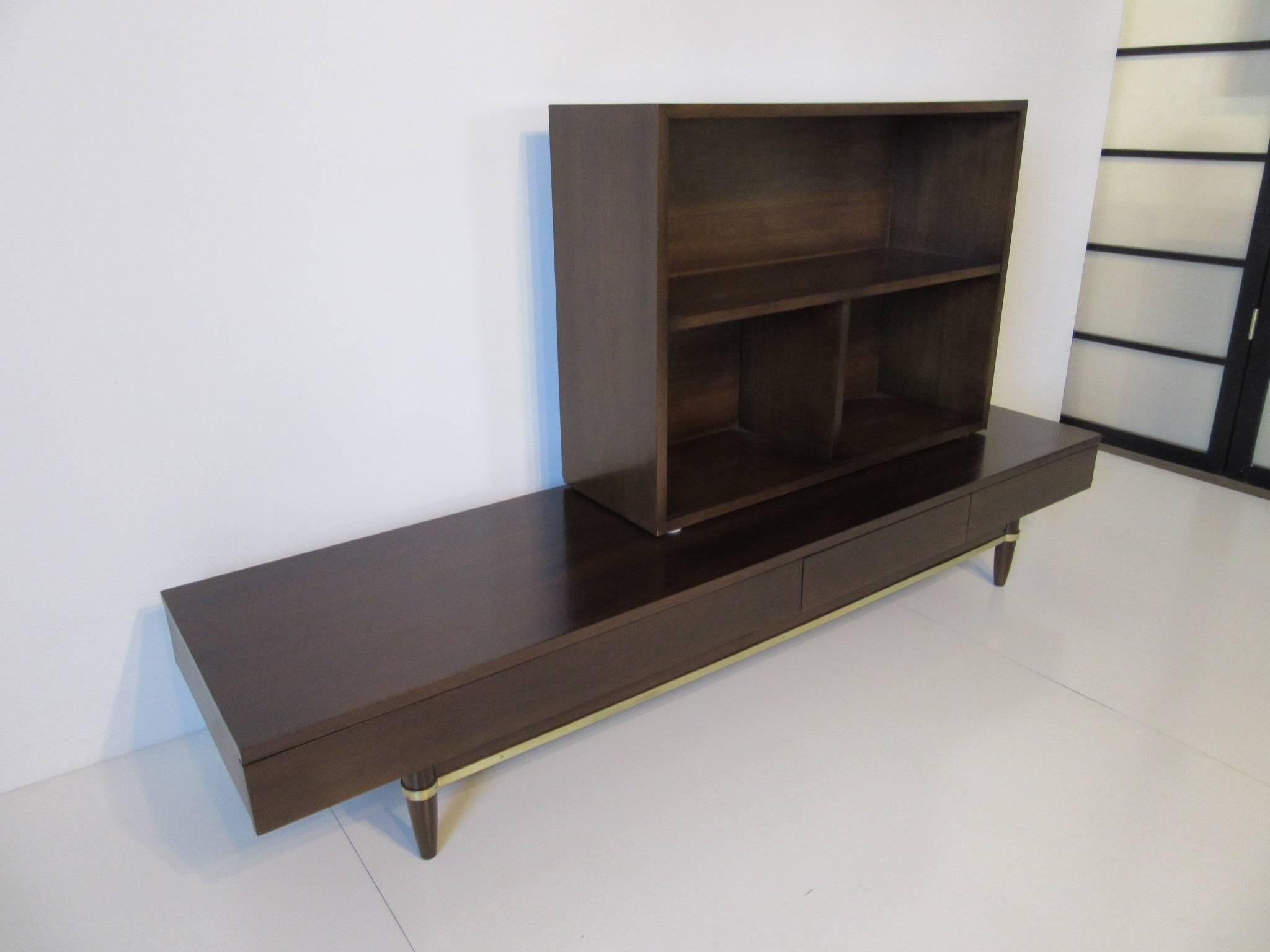 A two-piece ebony finished bookcase set with a lower three drawer platform accented with brass bands and having a upper three section bookcase. The bookcase can be adjusted to any area of the platform for ease of use. A well crafted piece