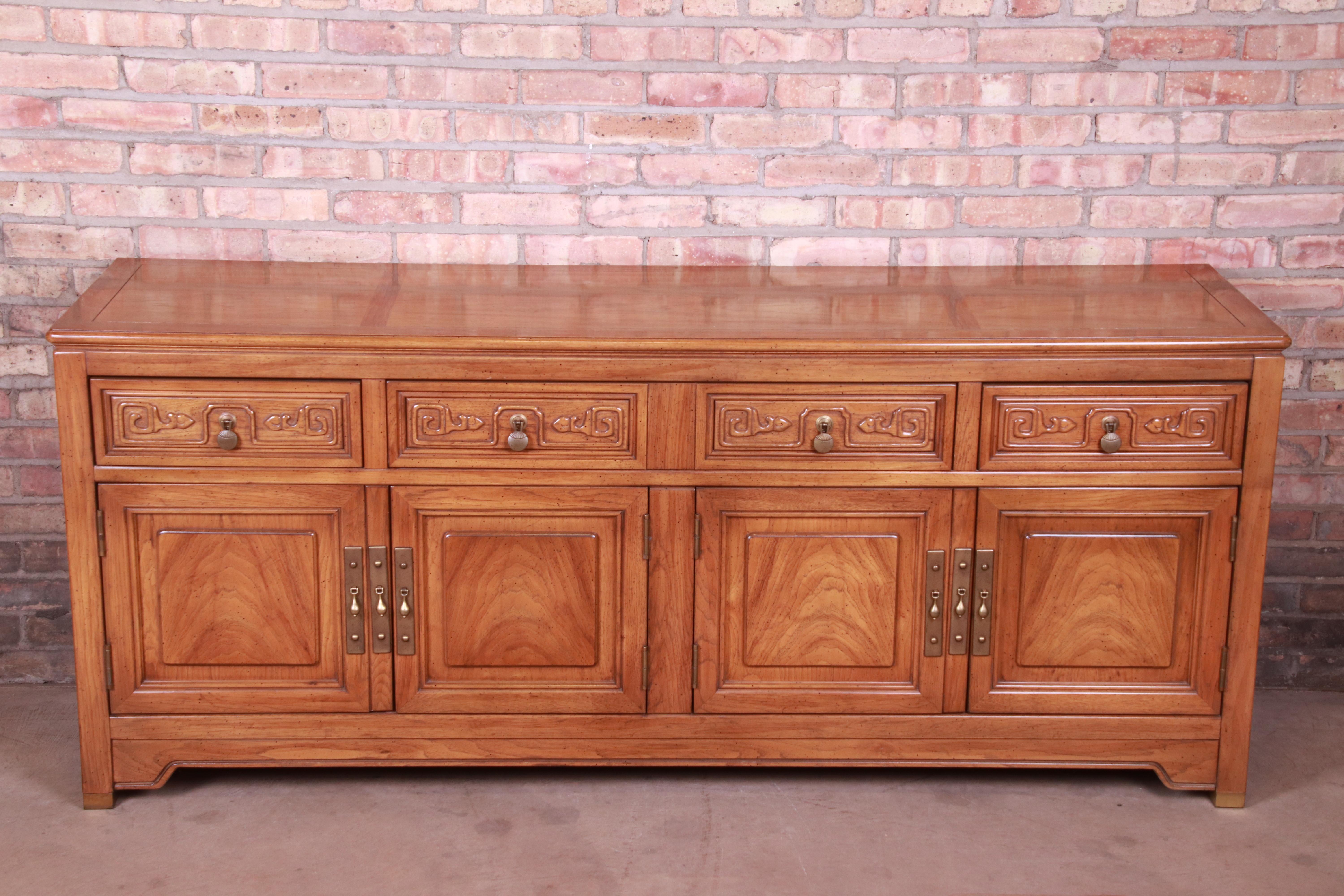 An exceptional midcentury Hollywood Regency chinoiserie sideboard credenza or bar cabinet

By American of Martinsville

USA, circa 1960s

Bookmatched walnut, with carved Asian details, original brass hardware, and brass-capped