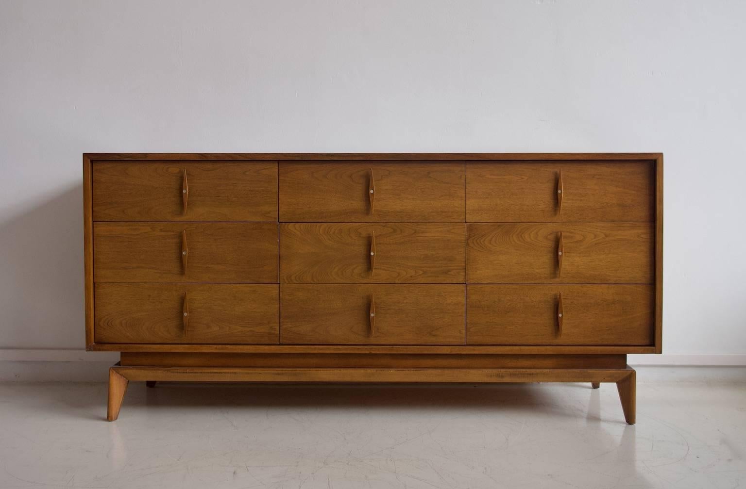 Sideboard or dresser with nine drawers and slightly slanted legs made of walnut wood. Manufactured during the 1950s by American of Martinsville. Label stamped inside one of the drawers.