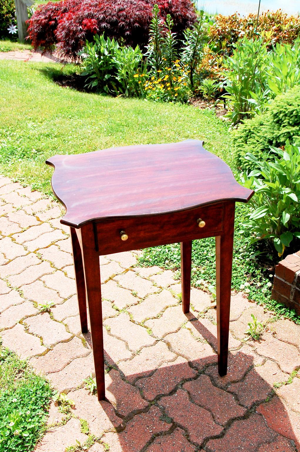 American Federal style one drawer side table with serpentine top and tapered legs. Under the table top is a hand written history of the table, probably written in 1909. It states the table with made by Ariel Hinckley for Betsy HInckley of Hallowell,