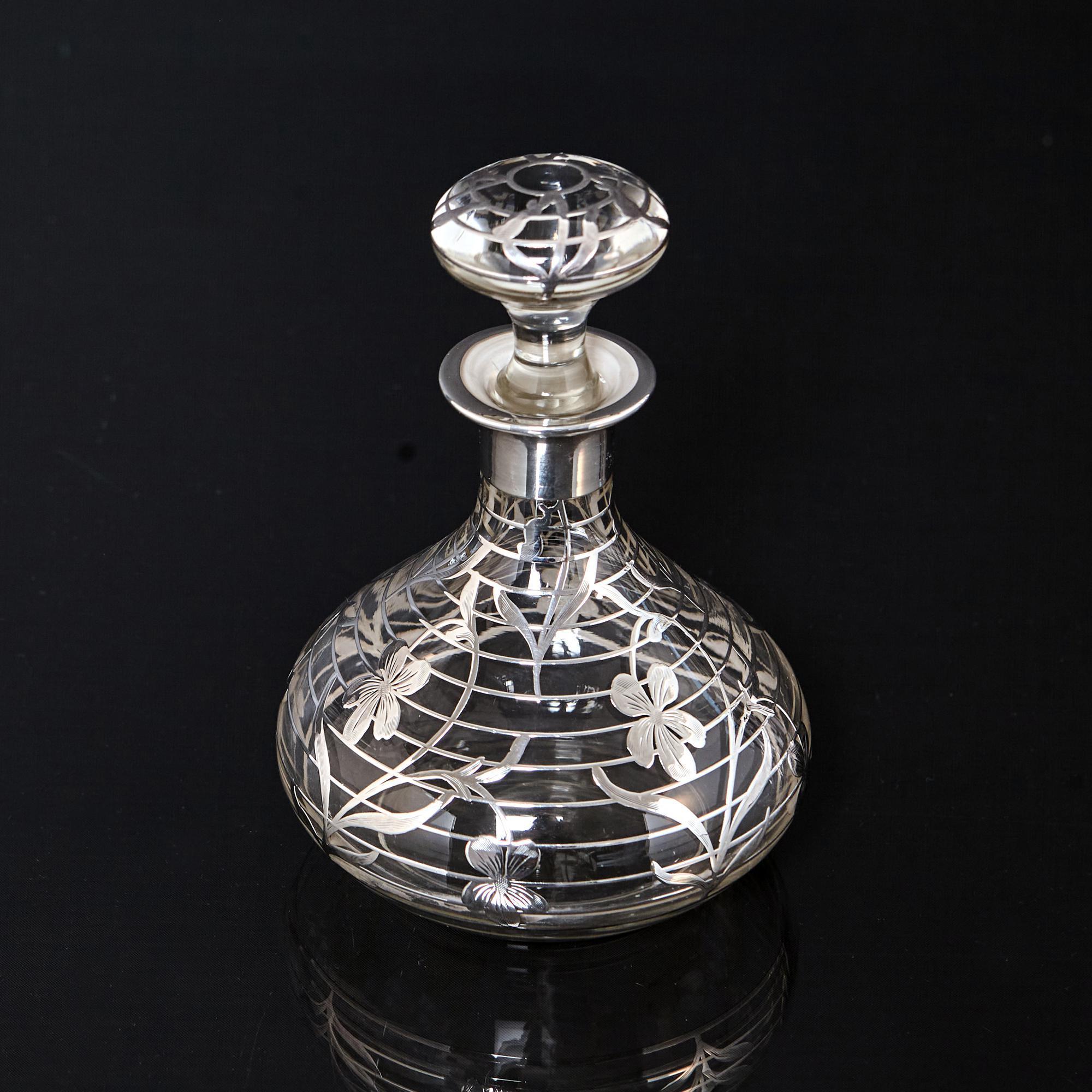 Hand-blown antique American glass perfume bottle overlaid with open-work silver banding and engraved floral decorations.

In 1889, the decorative technique of applying sterling silver designs to glass was patented by Oscar Pierre Erand and John