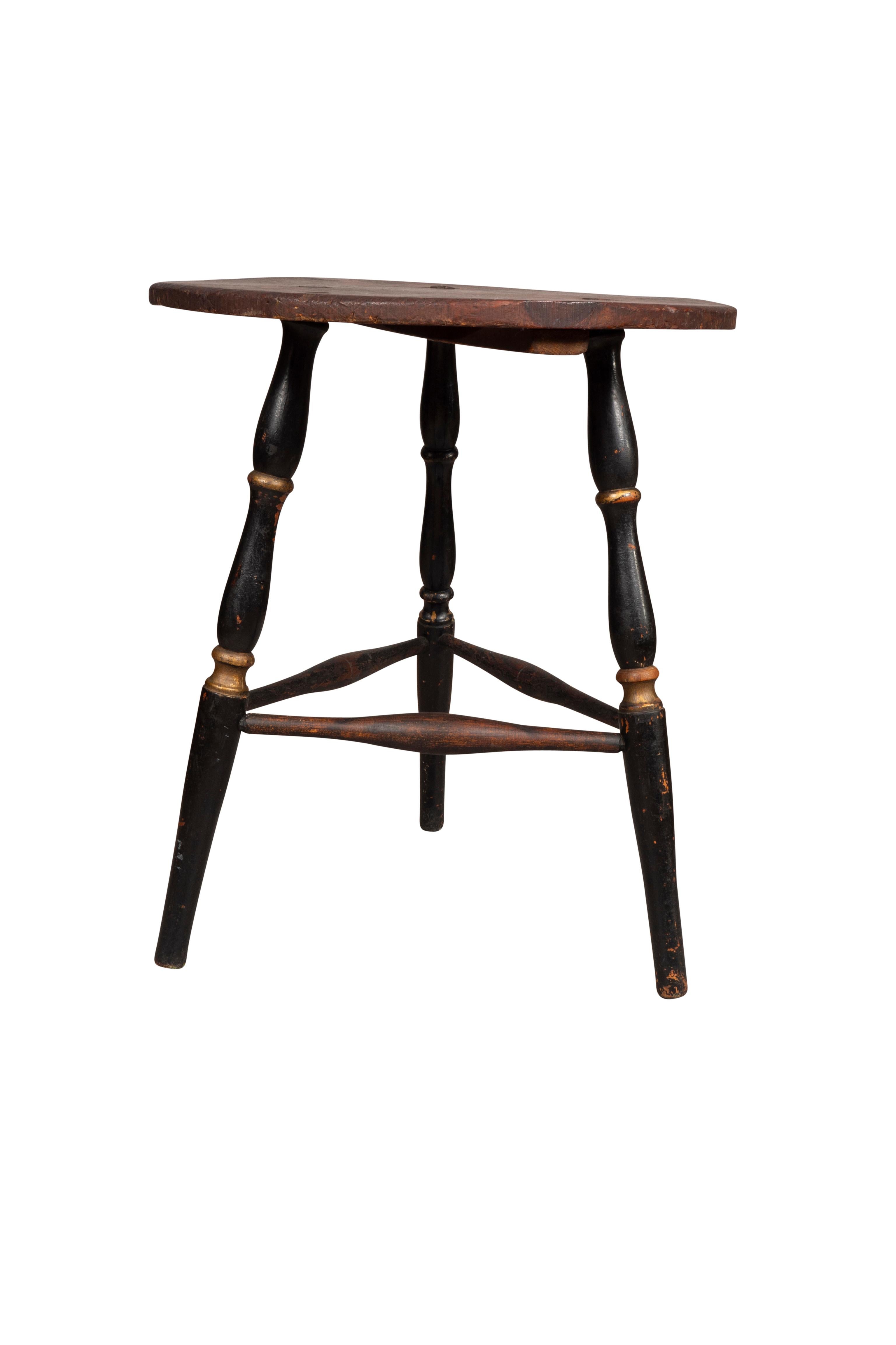 Scrubbed pine top with stains and scratches with three bamboo turned black painted legs with turned stretchers. New England origin.