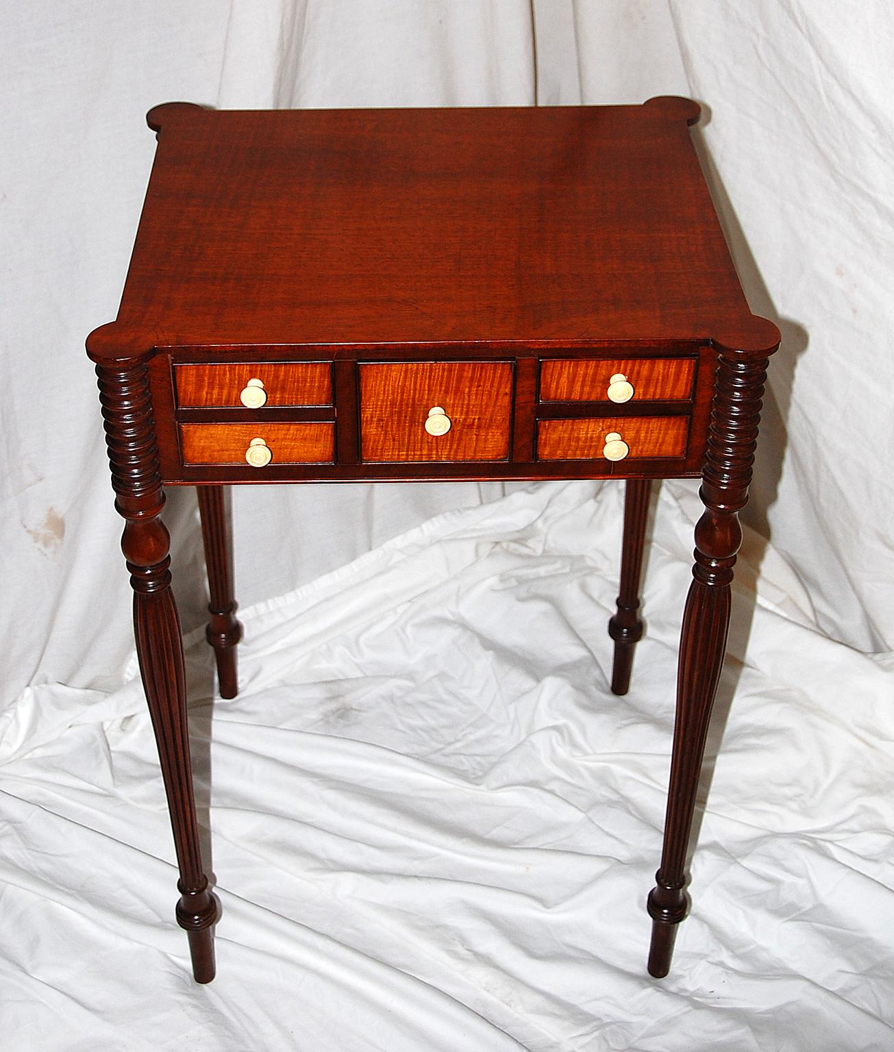 American pair of Boston Sheraton worktables in mahogany and bird’s-eye maple. The delicate reeded, turned and tapered legs culminate in ring carved turret tops which form cookie corners to the top of each table. The five small drawers on each table