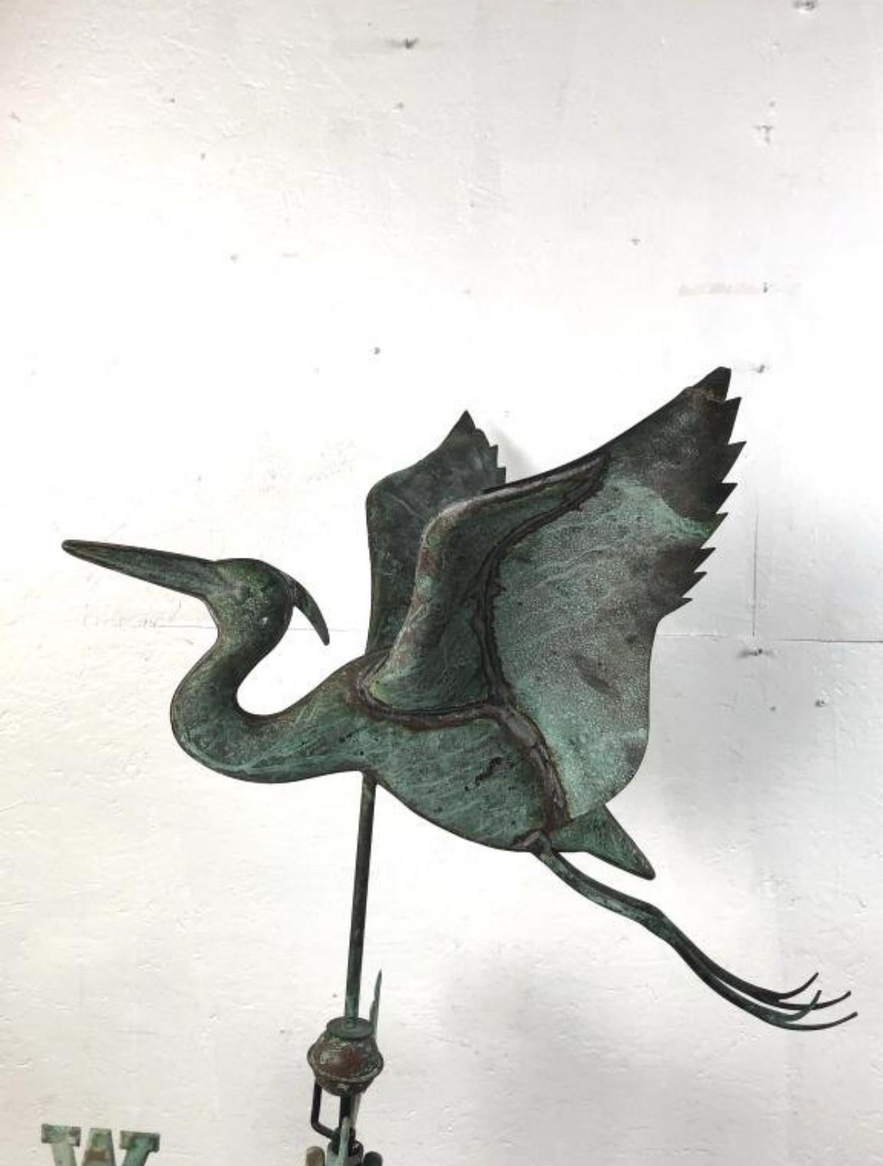 Girouette directionnelle cigogne américaine en cuivre patiné. Elle est posée sur un socle en fer contemporain. On pense qu'il date du 19e siècle. 