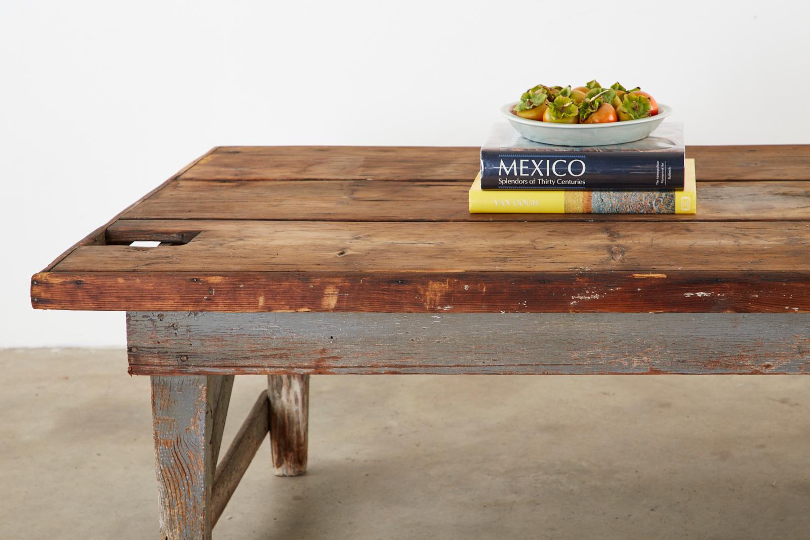 Rustic American Primitive work table or coffee table featuring a painted base. Constructed from pine having a thick plank top with two cut-outs. The top has a natural unpainted top with a beautifully aged patina. The top planks are bordered with