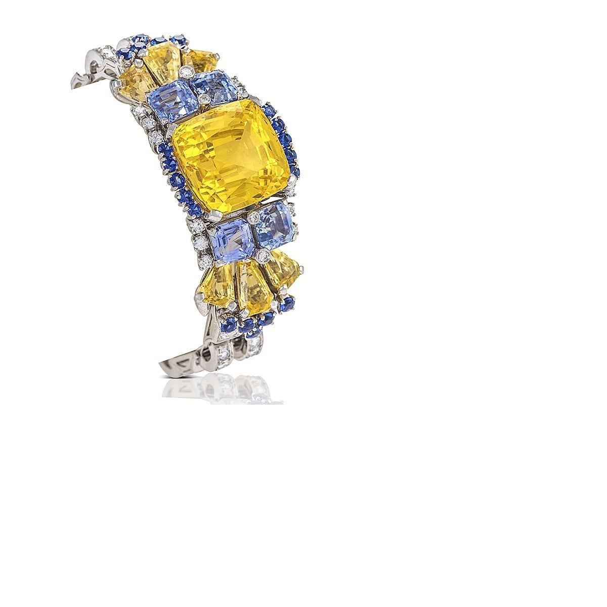 An American Mid-20th Century platinum bracelet with diamonds, yellow, light blue and, blue sapphires by Oscar Heyman. The bracelet has a square cushion yellow sapphire that weighs 41.47 carats, 4 Asscher-cut light blue sapphires with an approximate