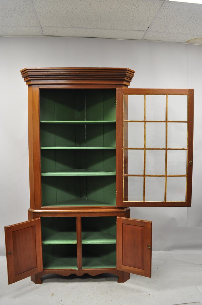 Antique American Primitive Colonial cherrywood wavy glass corner cupboard China cabinet. Item features 2 individual panels of antique wavy glass, green painted interior, solid wood construction, beautiful wood grain, 2 part construction, solid brass