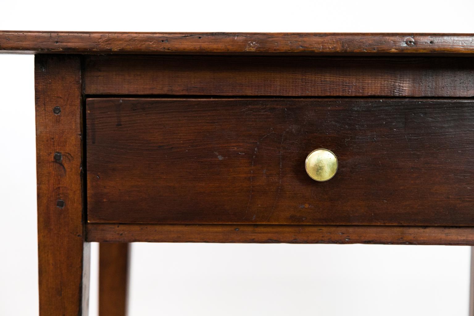 This American primitive heart pine one-drawer side table has exposed double peg construction, having a two board top with extensive overhang on the sides.