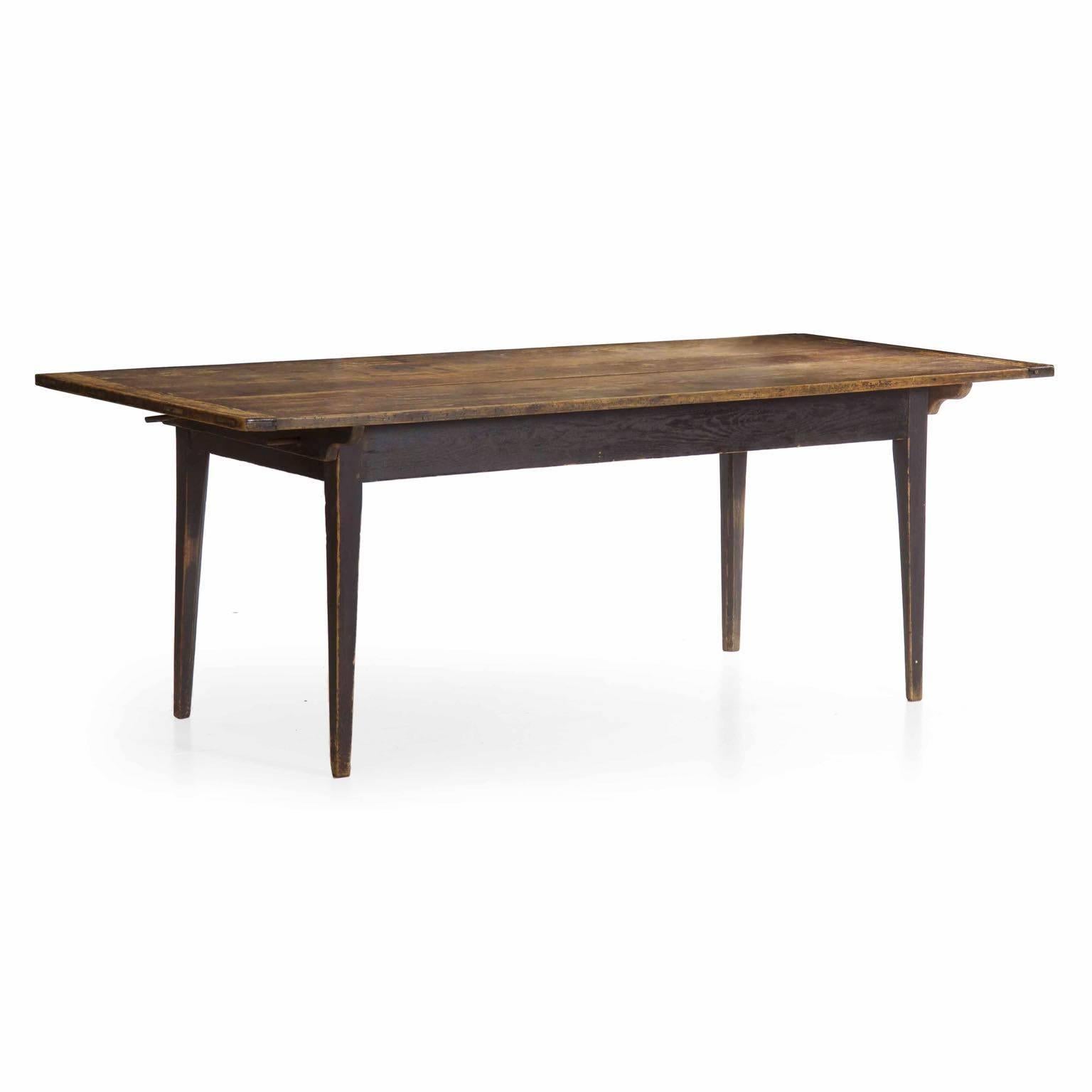 This gorgeous early scrubbed pine farm table was likely a product of the mid-Atlantic states during the last quarter of the 19th century. It is built with three large and beautifully patinated planks of pine flanked by breadboard ends that tenon