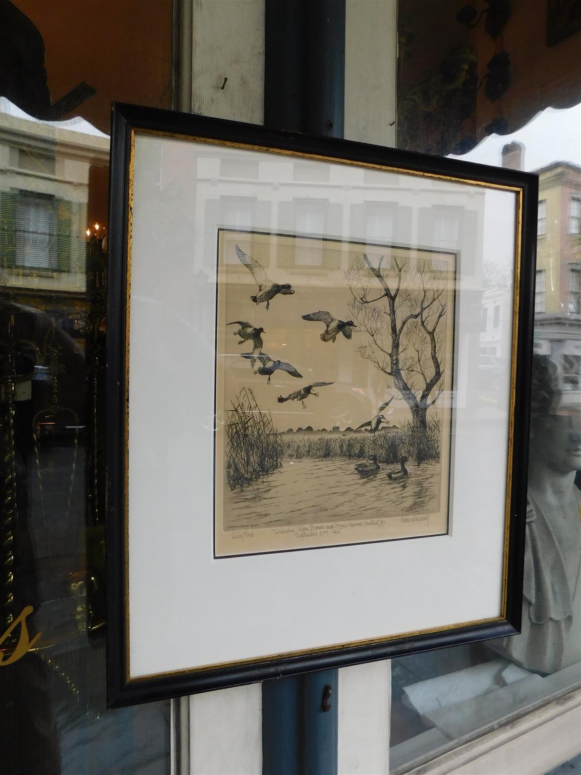 American print mallards in flight and swimming in marsh grass matted under glass in a painted and gilt frame. 