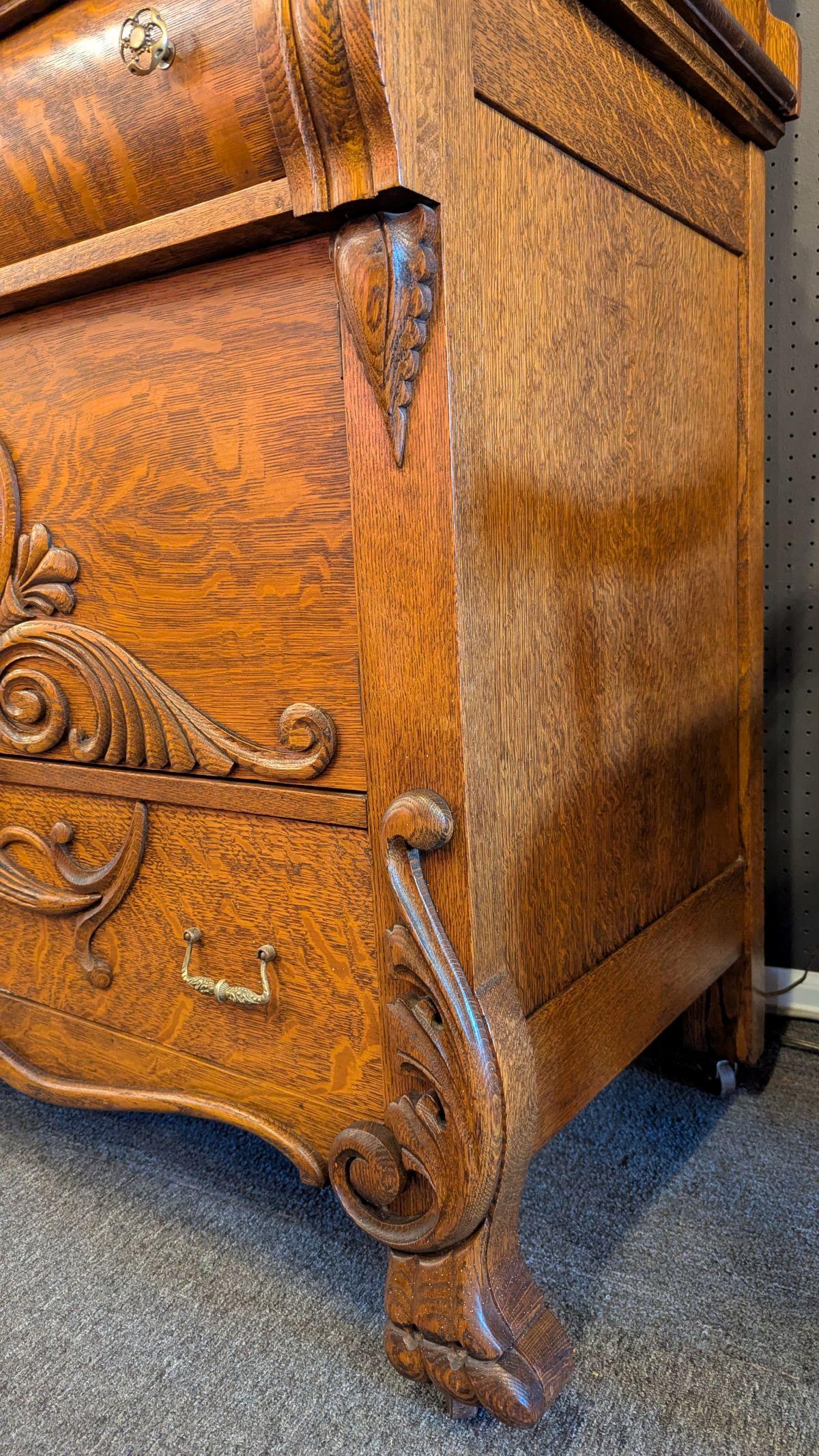 Impressive American quarter sawn oak Sideboard with carvings abound and stately Empire Scroll upper supports with claw bases, large claw feet, casters, large beveled mirror backboard with rare upper oval beveled mirror and cartouche crest.  Center