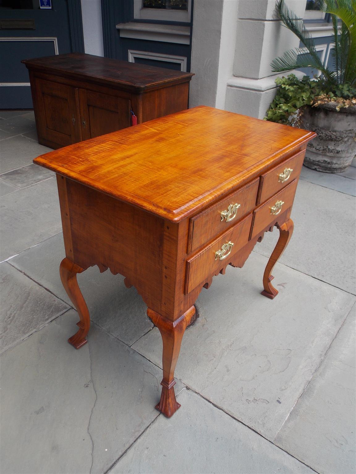 American Queen Anne curly maple four drawer lowboy with a carved molded edge, pegged mortise and tenon joints, rose head nails, period brasses, carved scalloped skirt, and terminating on molded squared cabriole legs with cuffed Spanish feet,