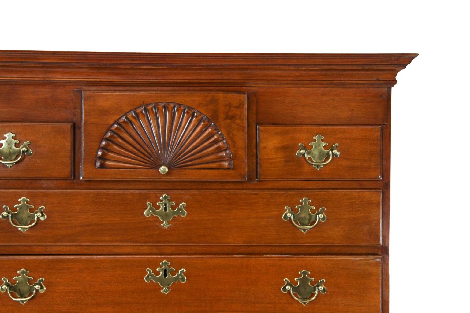 American Queen Anne flat top maple highboy, with cove cornice, upper section with carved fan drawer flanked by two drawers over four drawers retaining original brass pulls. The lower section with long drawer above fan carved drawer flanked by two