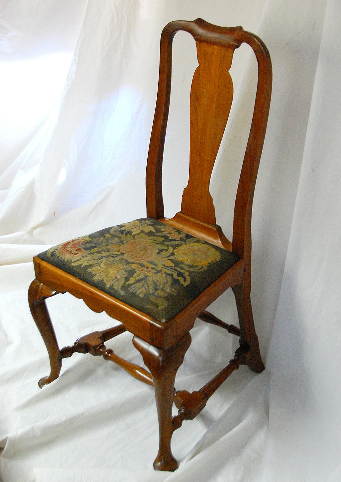American Queen Anne period walnut sidechair from a Boston cabinetmaker. This elegant chair is distinguished by its cabriole legs, pad feet and vase form splat. The block and turned cross stretcher provides extra strength while the shaped skirt adds