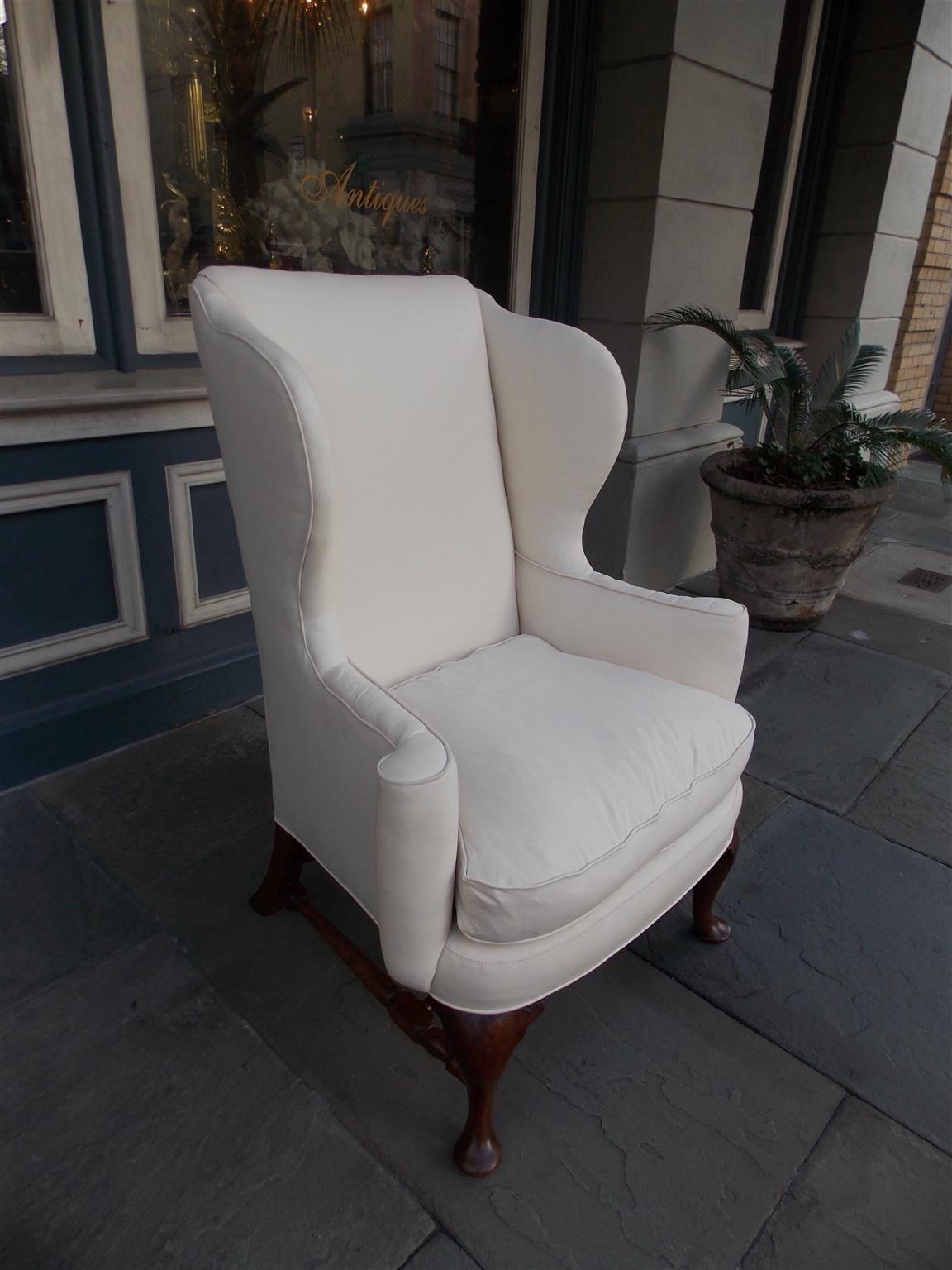 American Queen Anne walnut wing back chair with straight back, flared wings, flanking scrolled arms, removable seat cushion, bulbous turned ringed stretchers, and terminating on the original pad feet with rear splayed legs. Secondary wood consist of