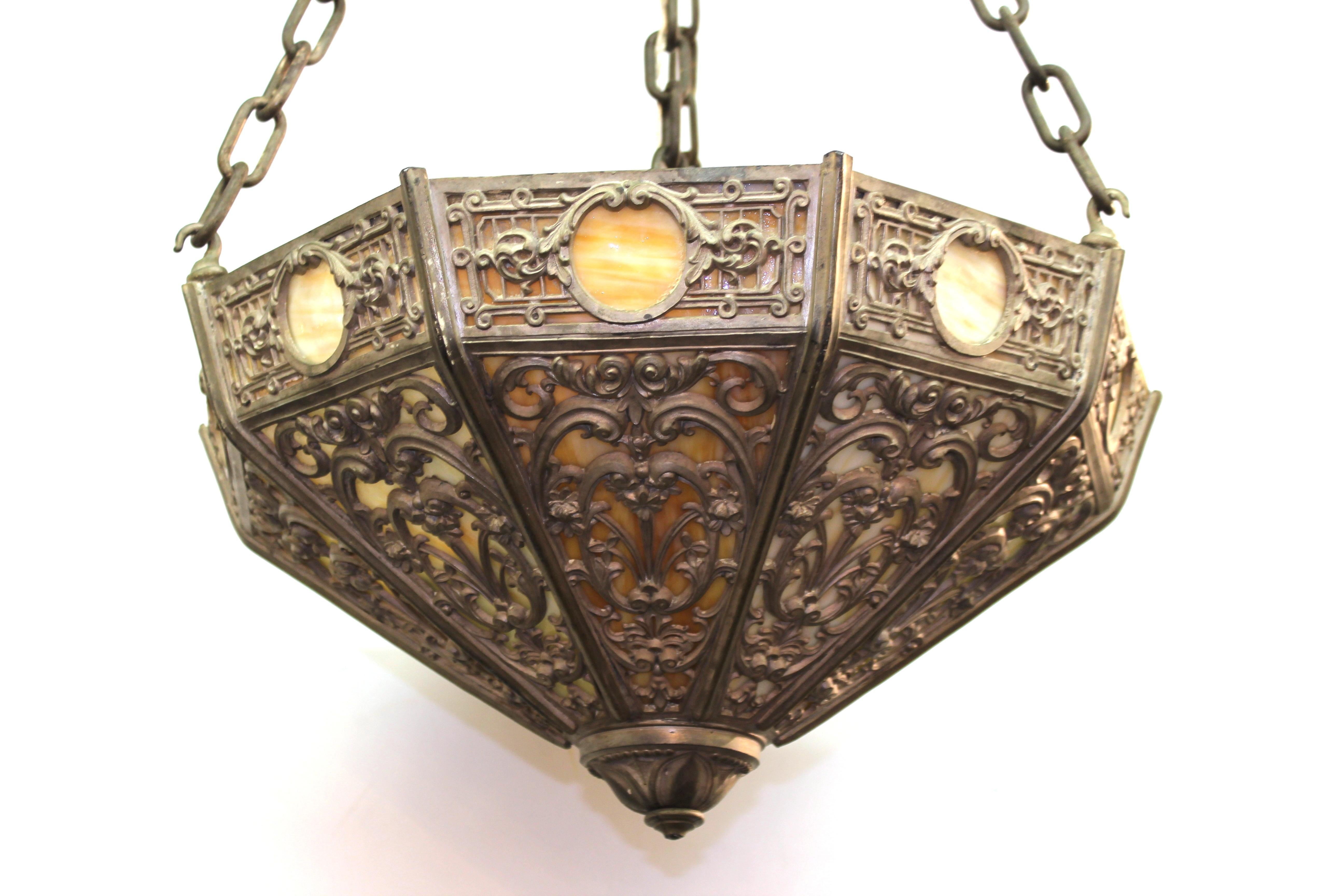 Renaissance Revival turn-of-the-century pendant with an elaborate metal frame designed with a decorative grotesque motif, with a back layer of marbled glass panels. The piece was made in the United States during the late Victorian era and has