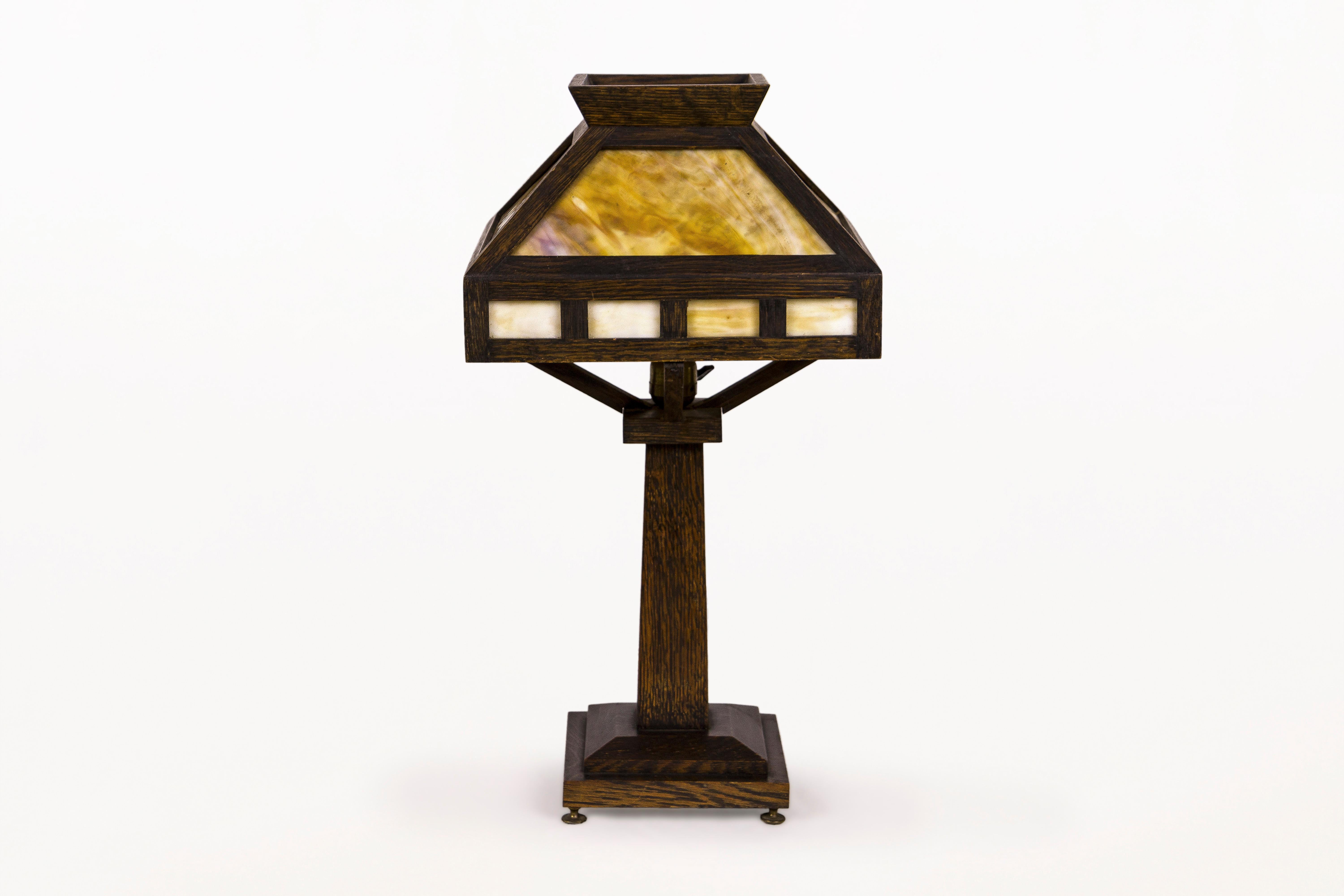 American Rustic Mission oak table lamp
Classic Arts & Crafts oak table lamp.
The lamp has a four sided shade with caramel slag glass insert and a footed base.
All original finish with a rich patina.
Lamp is in very good original condition with