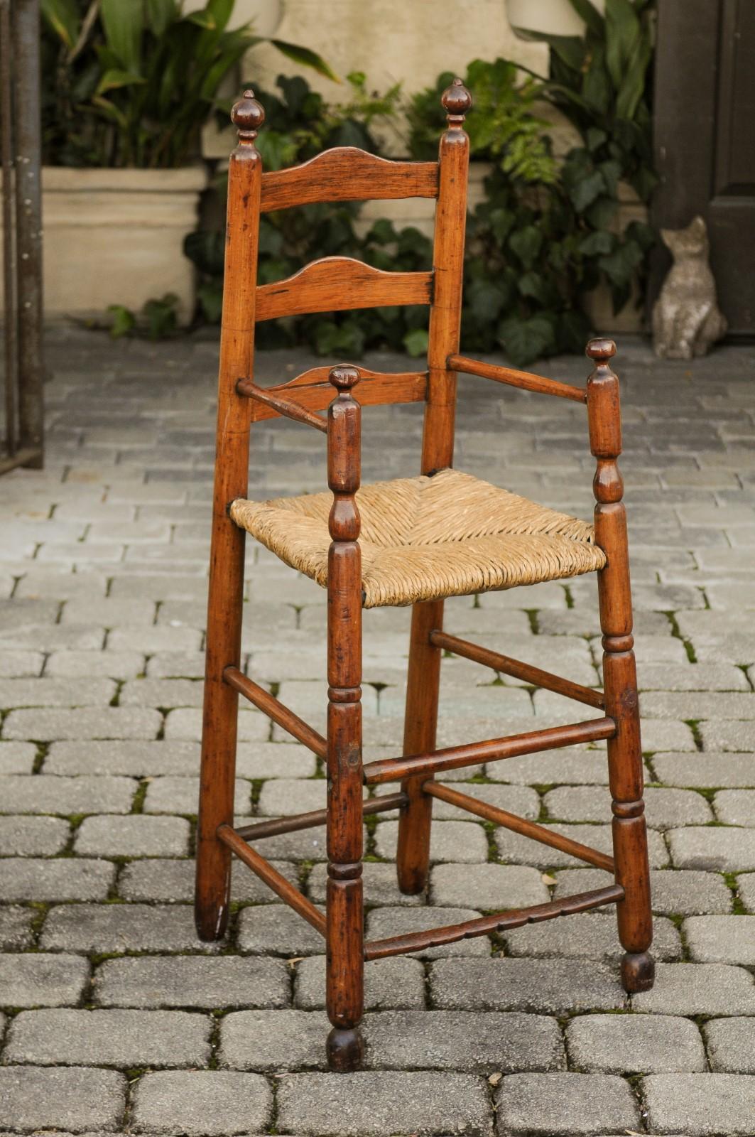 An American rustic pine child's high chair from the early 20th century with rush seat. Experience the warmth and nostalgia of early American craftsmanship with this rustic pine child's high chair from the early 20th century, complete with a