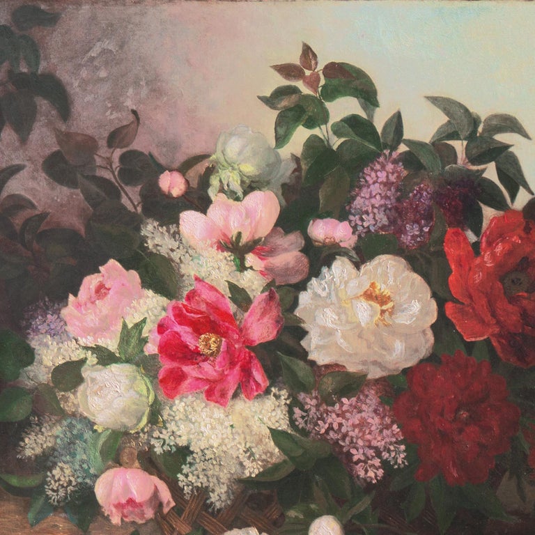 A well-observed and finely-painted, late 19th century still-life showing a variety of fresh-cut flowers informally arranged in a large, woven-wicker basket, dramatically lit in a garden setting with a view beyond towards a lilac and teal-blue sky. A