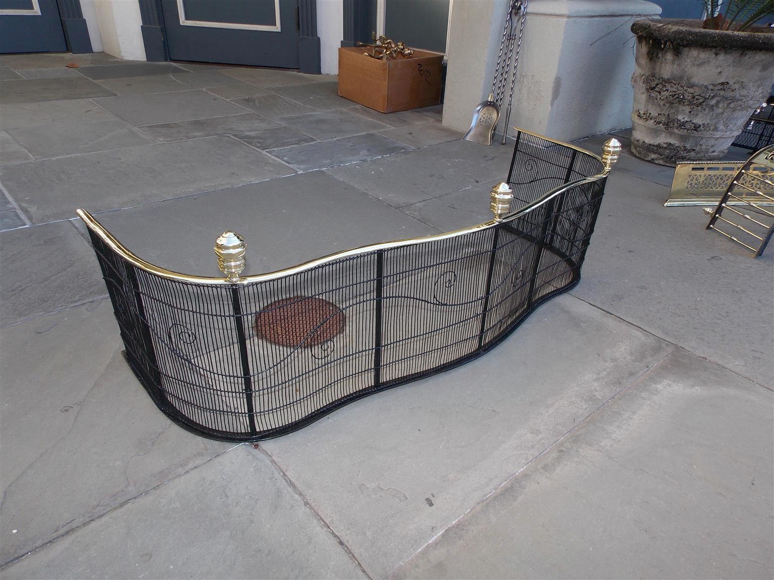 American Empire serpentine fire place fender with bulbous faceted brass finials, brass rail top, and pleasing scrolled artistic wire work, Philadelphia, Early 19th century.