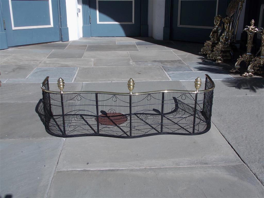 American Empire serpentine fire place fender with bulbous faceted brass finials, brass rail top, and pleasing scrolled artistic wire work. Philadelphia, Early 19th century.
 