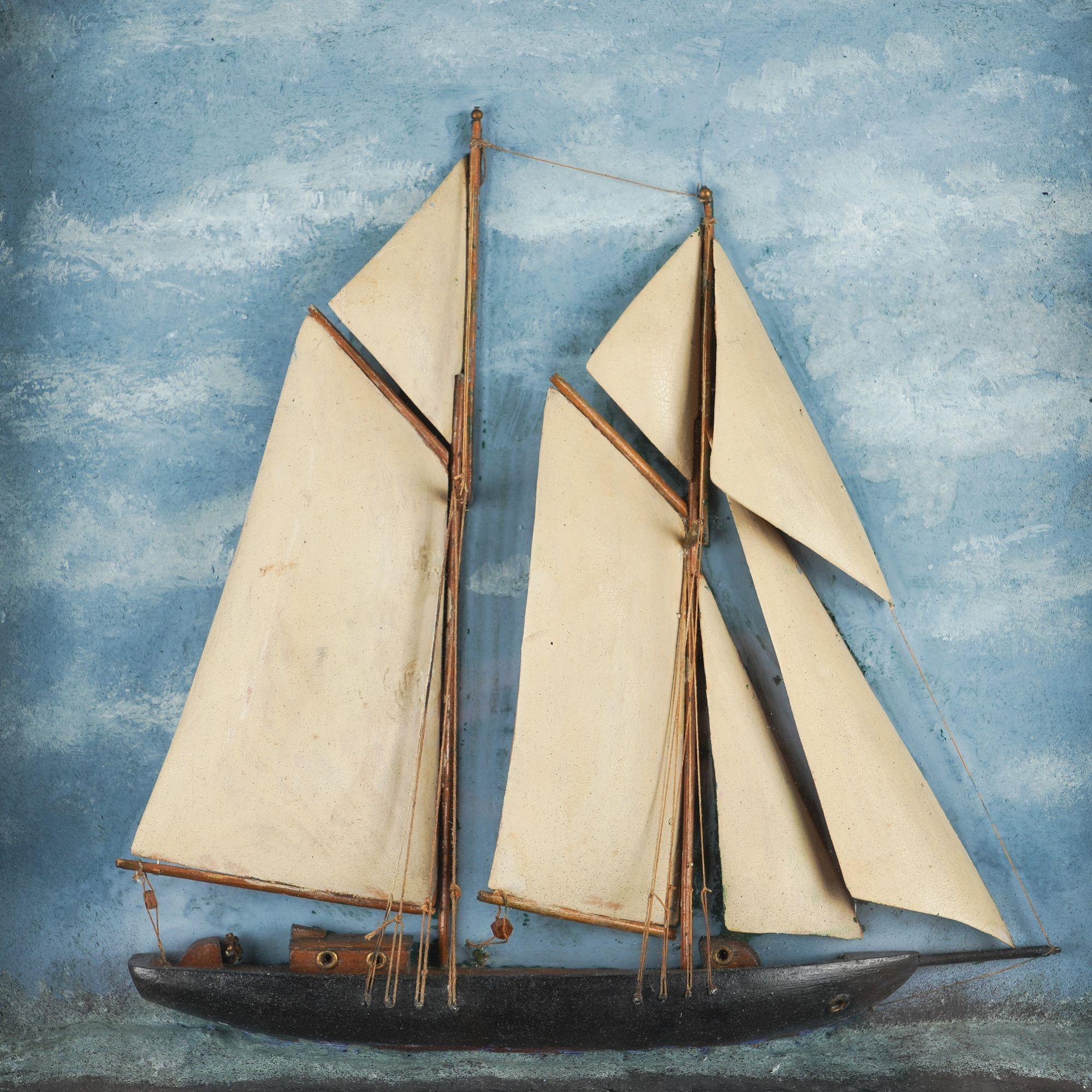 Half ship diorama of a two masted sailboat on a painted plaster sea, which is set against a sky of painted clouds. The work is mounted in a painted wood shadow box and fitted with period glass. The shadow box frame has a slight irregularity to the