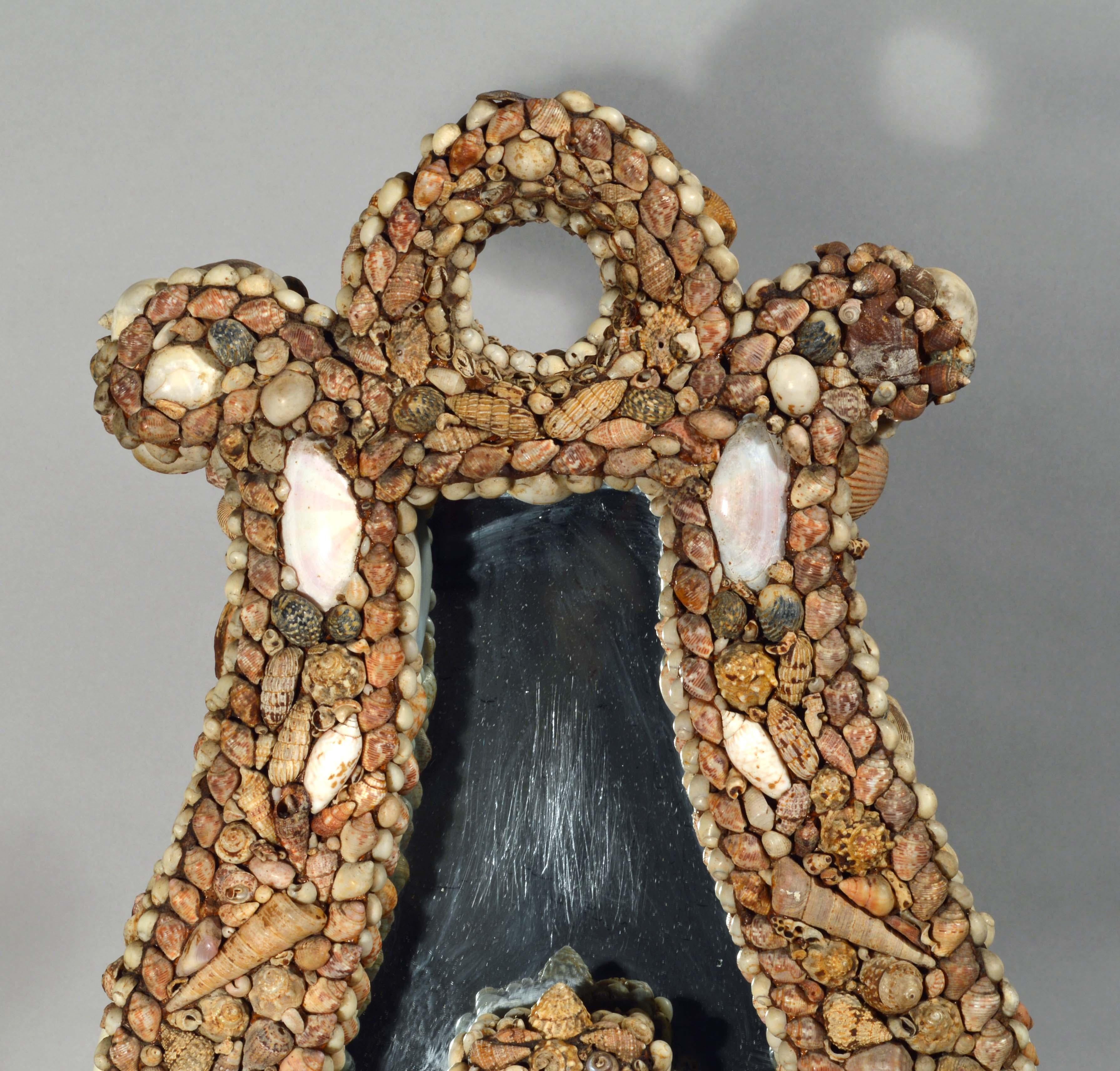 American shellwork standing mirror in the form of a Harp,
circa 1885

The unusual 19th century American shellwork standing mirror is in the form of a harp. The mirror is decorated with a mosaic of a delightful variety of naturally colored shells