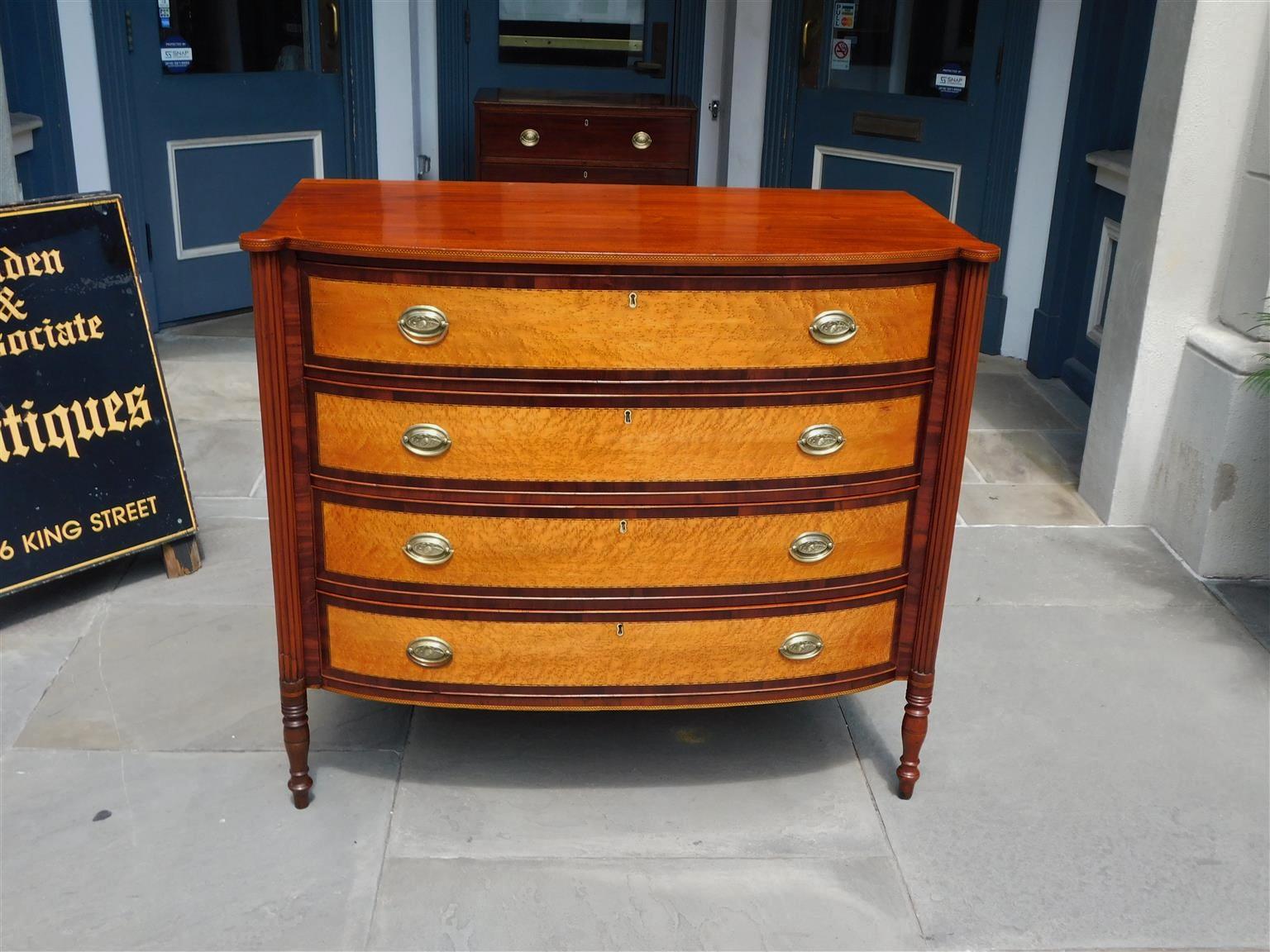 American Sheraton Mahogany and Birdseye Maple graduated four drawer bow front chest with carved outset corners, checkered inlays, flanking reeded columns, oval brasses, and resting on the original turned bulbous ringed legs. New England, Early 19th