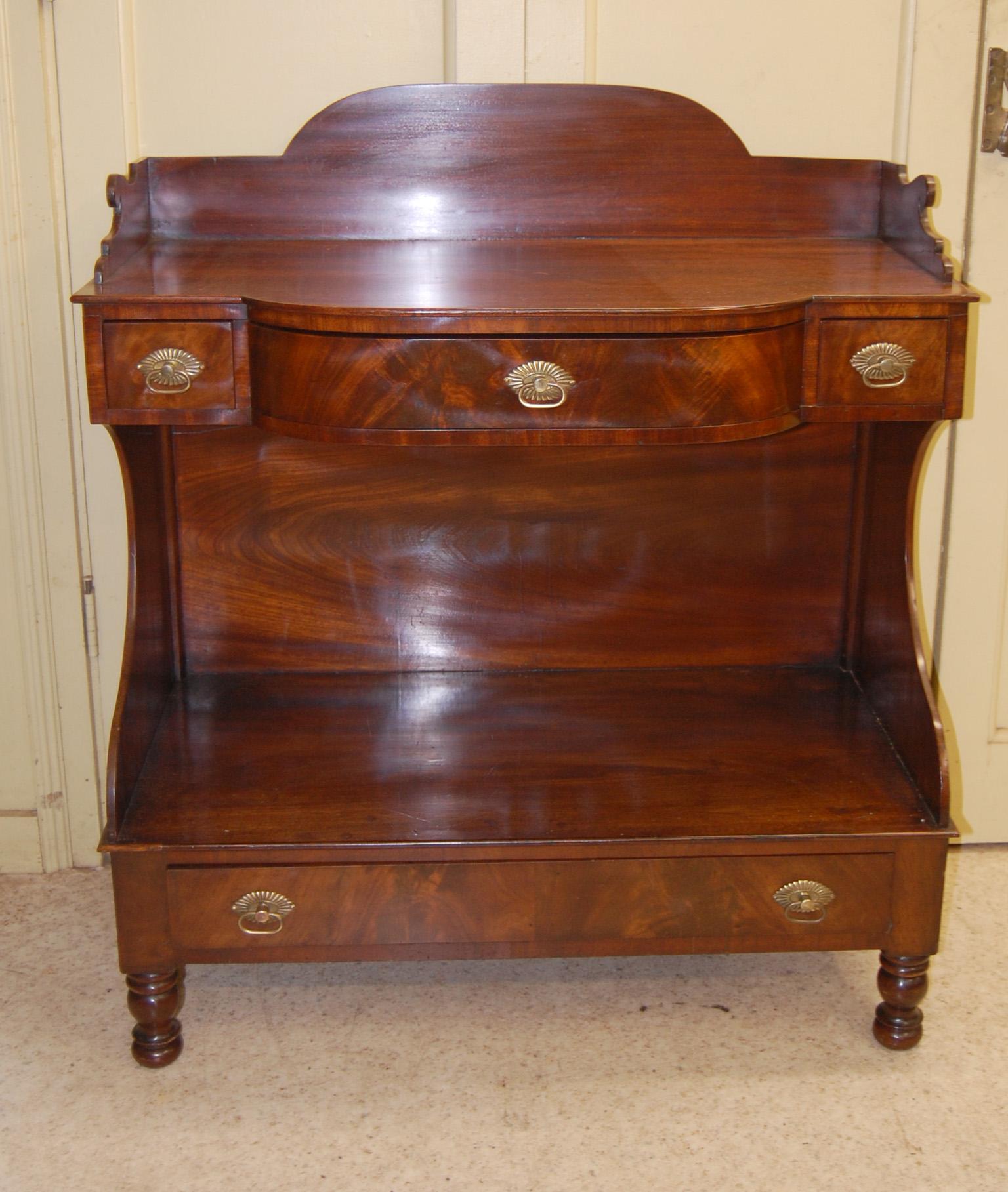  American Sheraton mahogany bowfront breakfront sidetable.  This unusual form has a galleried top, three drawers below the top surface and one long drawer below the lower surface, shaped sides, all standing on turned legs. The drawer fronts are