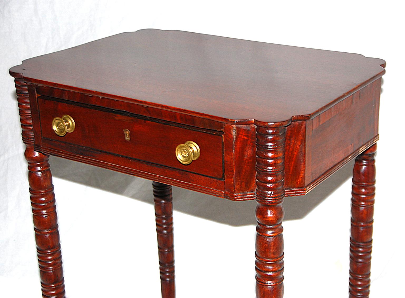 American Sheraton period one-drawer workstand in mahogany. The tapered ring turned legs with turret tops are unusual and indicate a probable Boston origin. The concave corners of the body of the stand add interest and architectural dimension to this