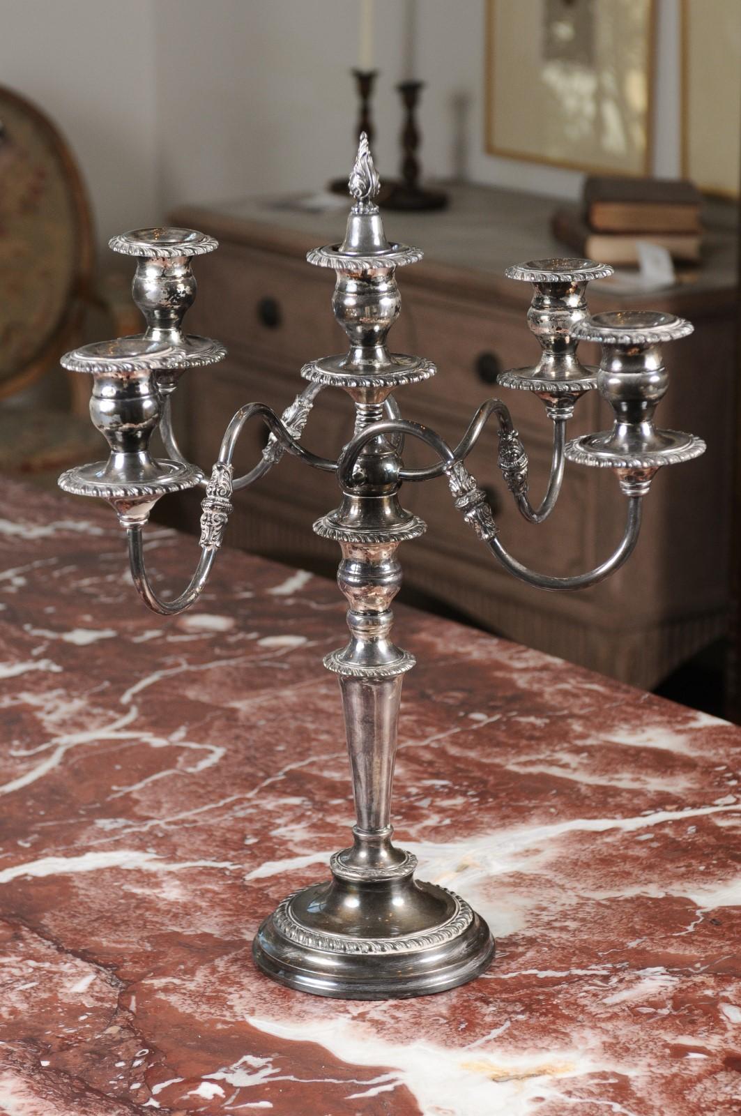 An American silver plated four-arm candelabra from the 20th century, with foliage and scrolling accents. We are immediately drawn to the elegant presence of this American candelabra, presenting a silver plated structure. A central shaft is tapering