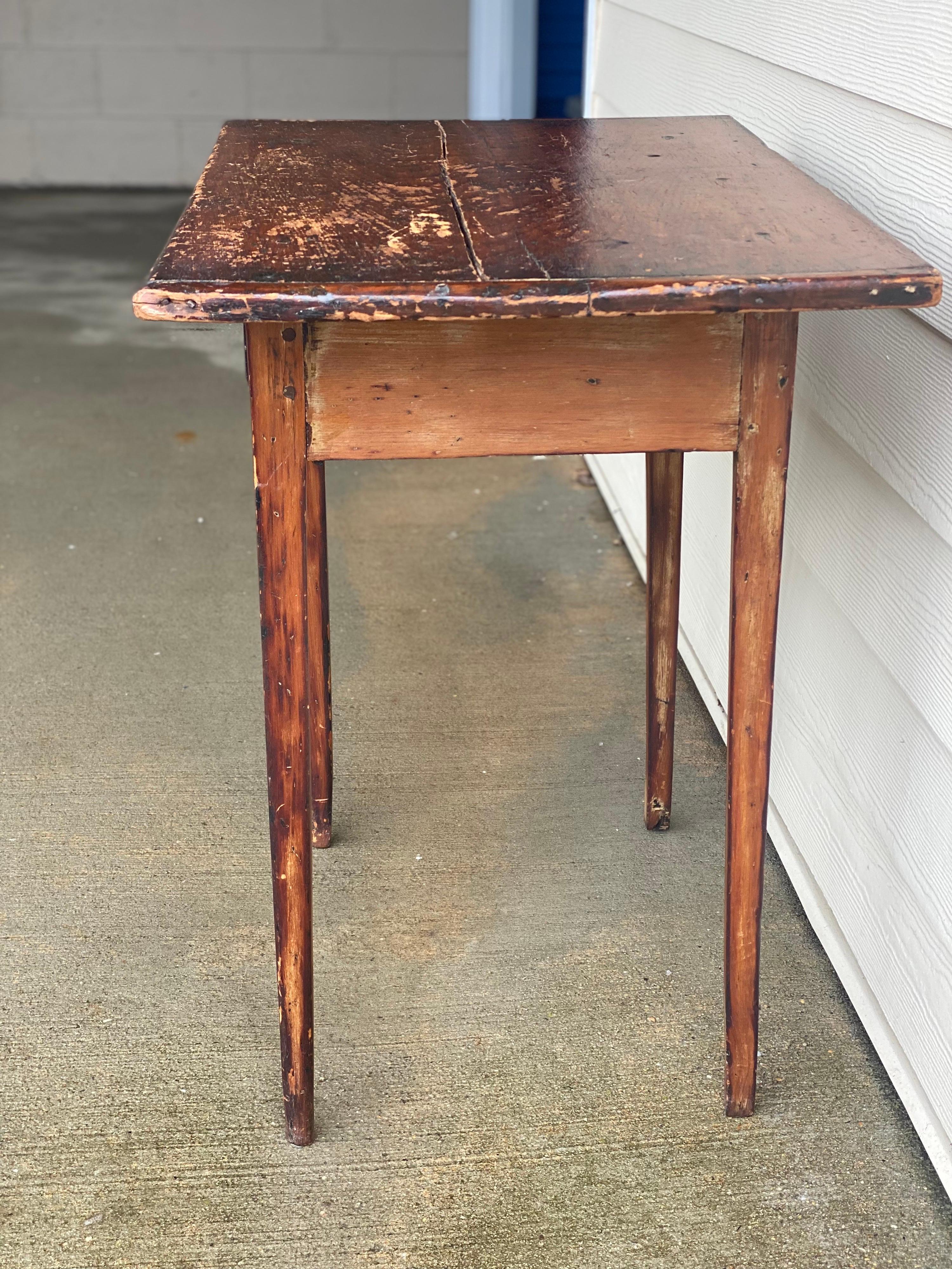 American single drawer rustic end table, 20th century.
Charming simple rustic table with clean lines, tapered legs, and a round brass knob. Some separation to the top. Knicks and wear to the finish. Overall stable condition with a rustic patina.

