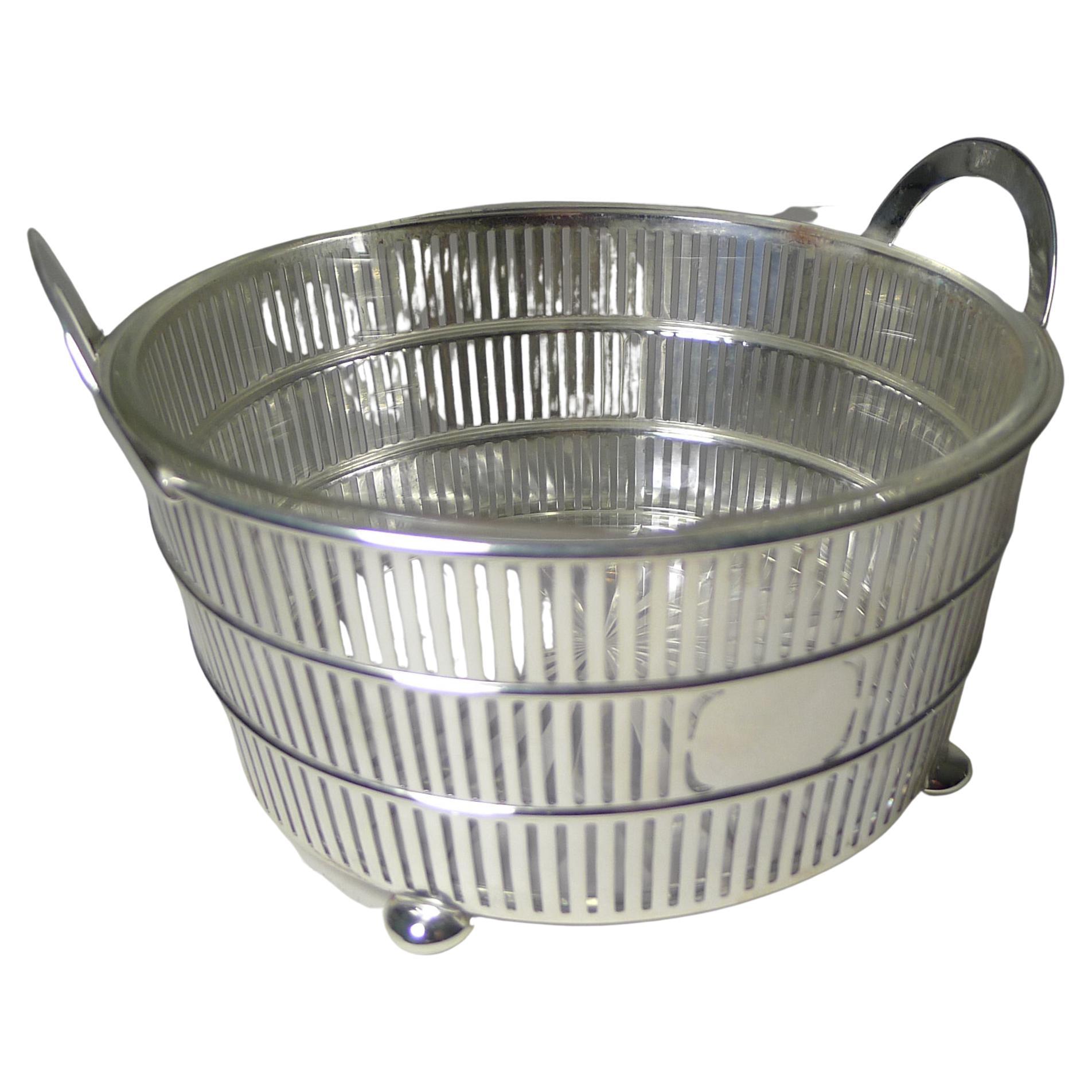 A handsome glass lined bowl with a great look to suit any interior from traditional to modern. The basket is made from American sterling silver with clean lines, reticulated or pierced with a vacant cartouche to the front.

The underside retains