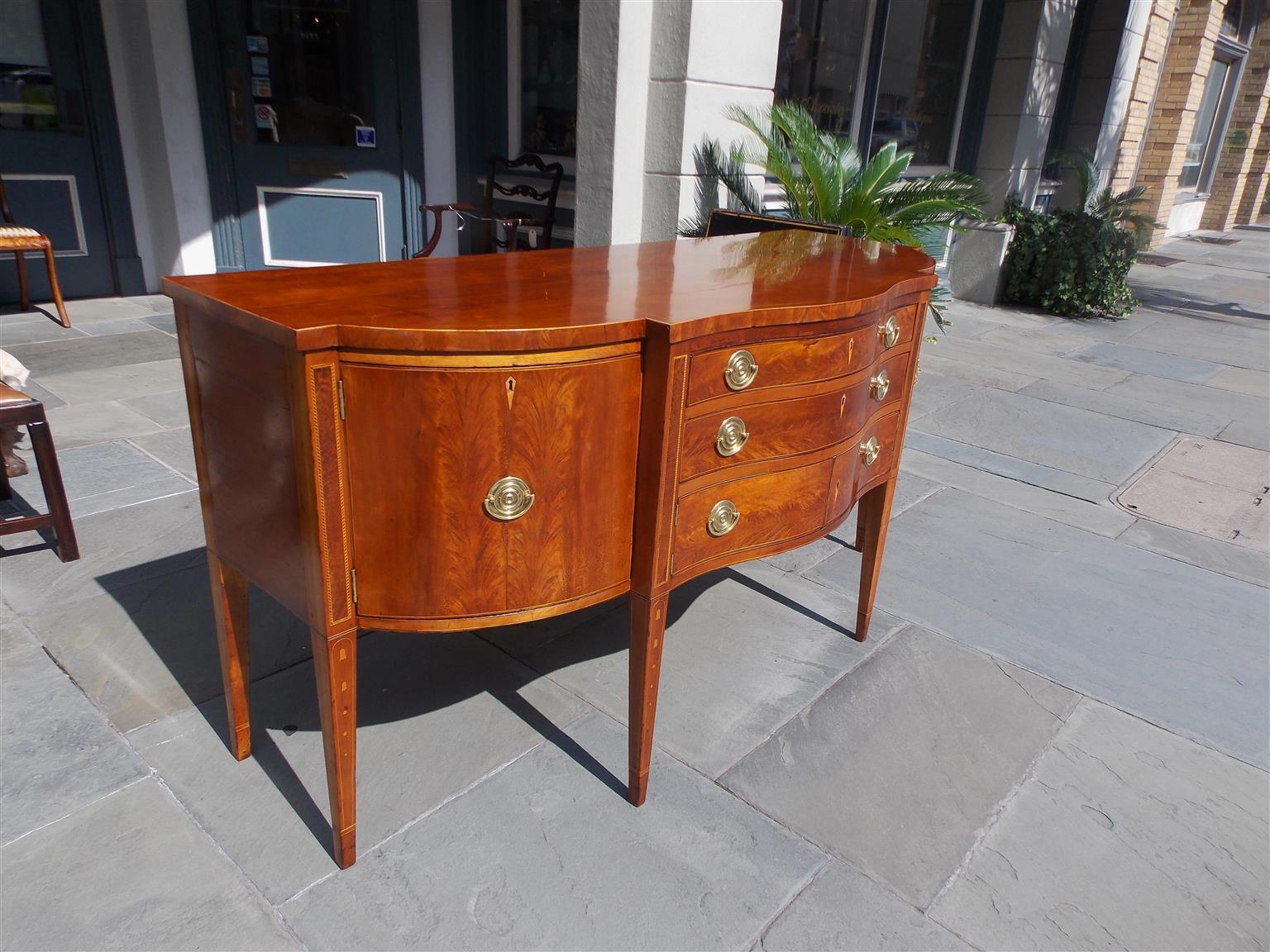 American Southern Hepplewhite cherry serpentine sideboard with two centered drawers over flanking hinged doors revealing interior storage, a single hinged cabinet and deep drawer on opposite ends, circular brass pulls, figured walnut with string and